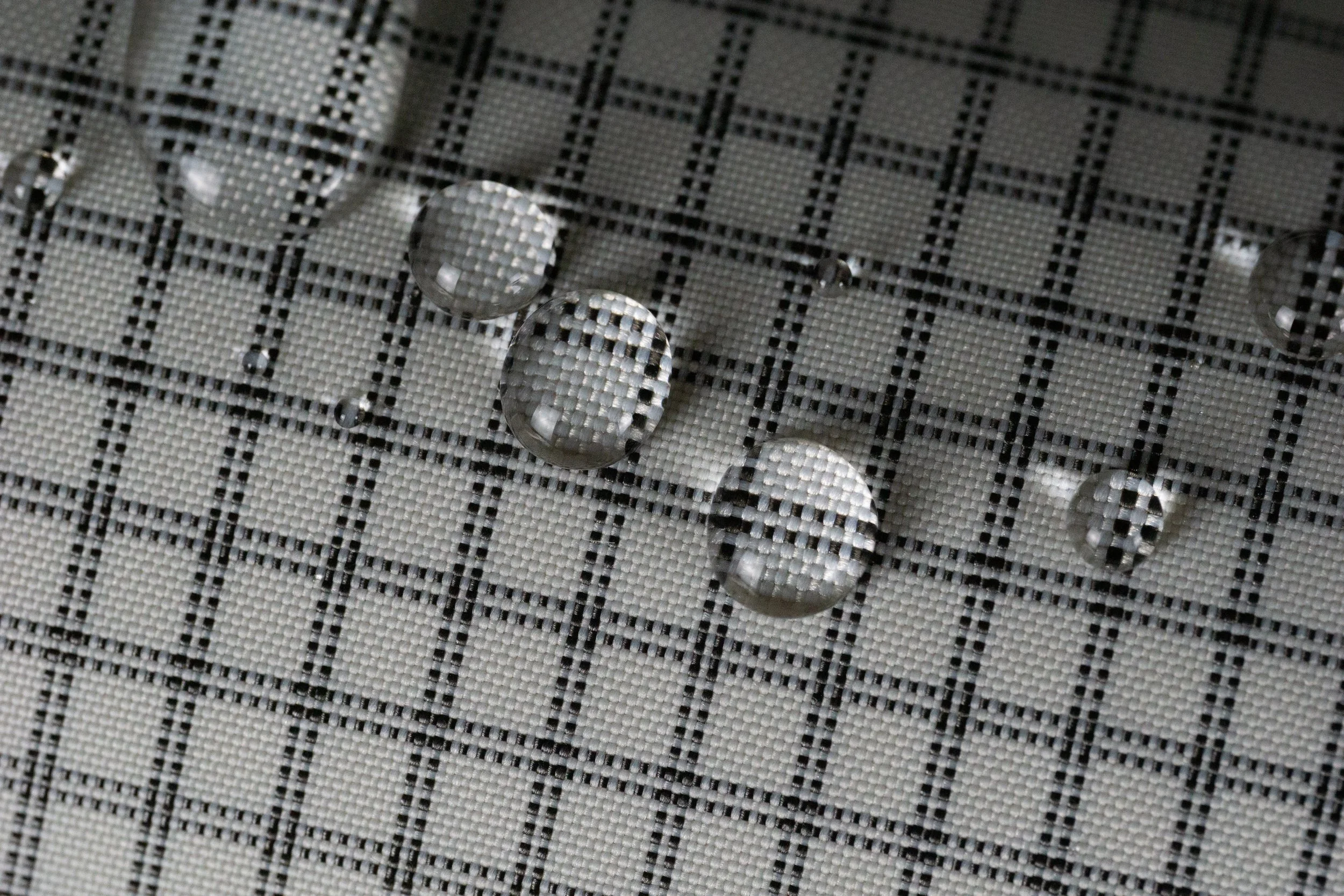 Gouttes d'eau sur un tissu en plastique noir et blanc à motif en damier.
