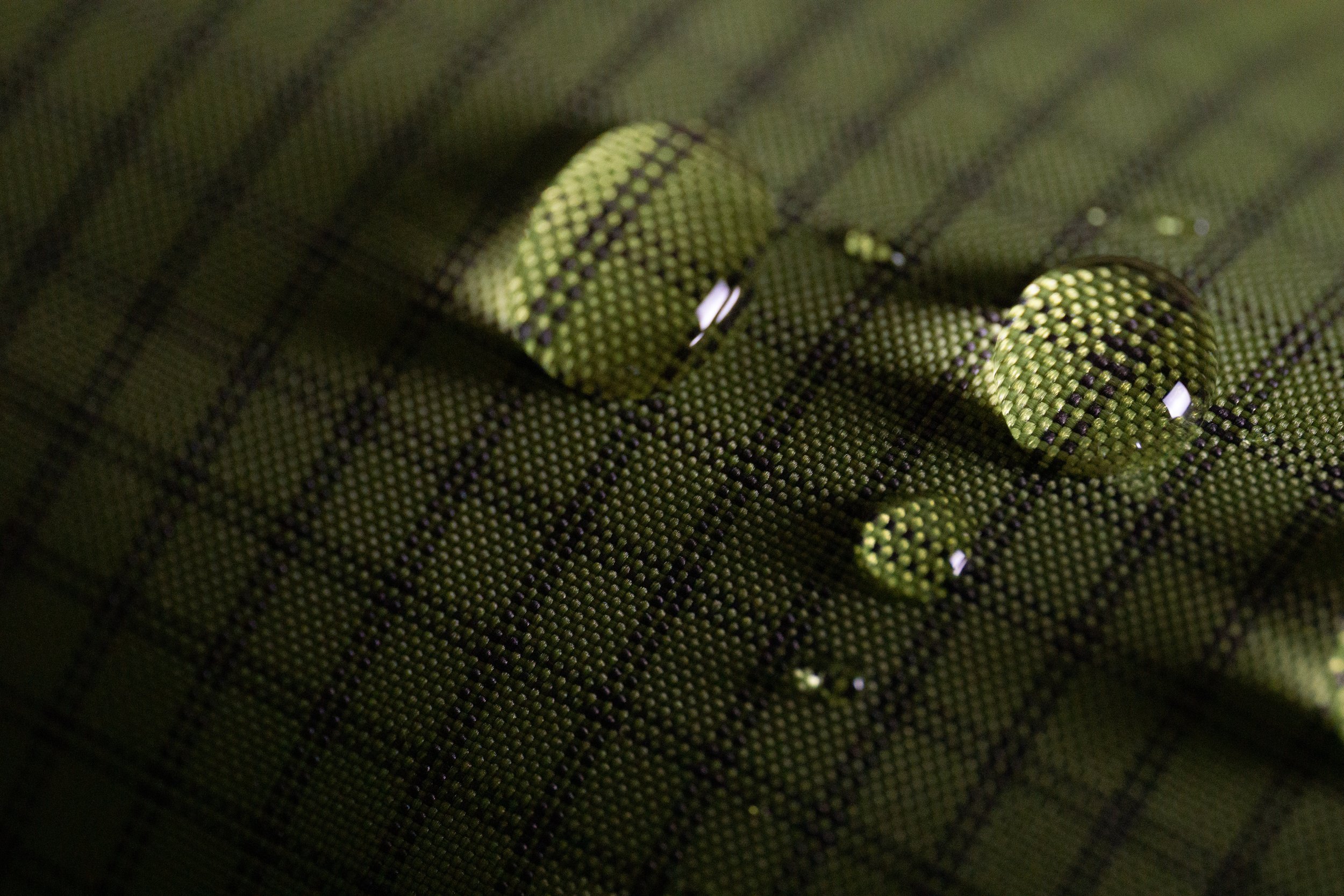 Gouttes d'eau sur un tissu vert à motif à lignes noires