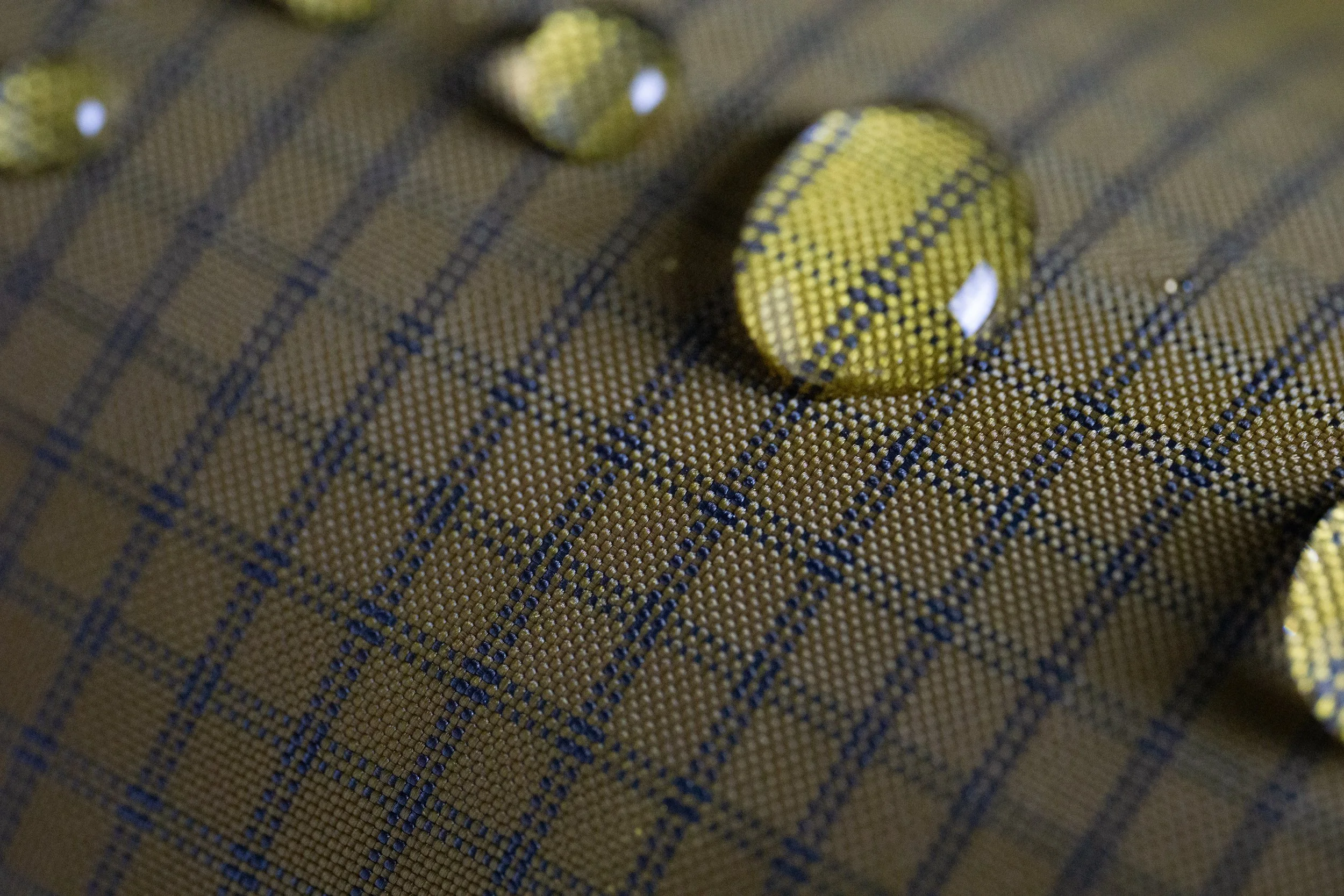 Gros plan de boutons en tissu à motif à carreaux beige et bleu.