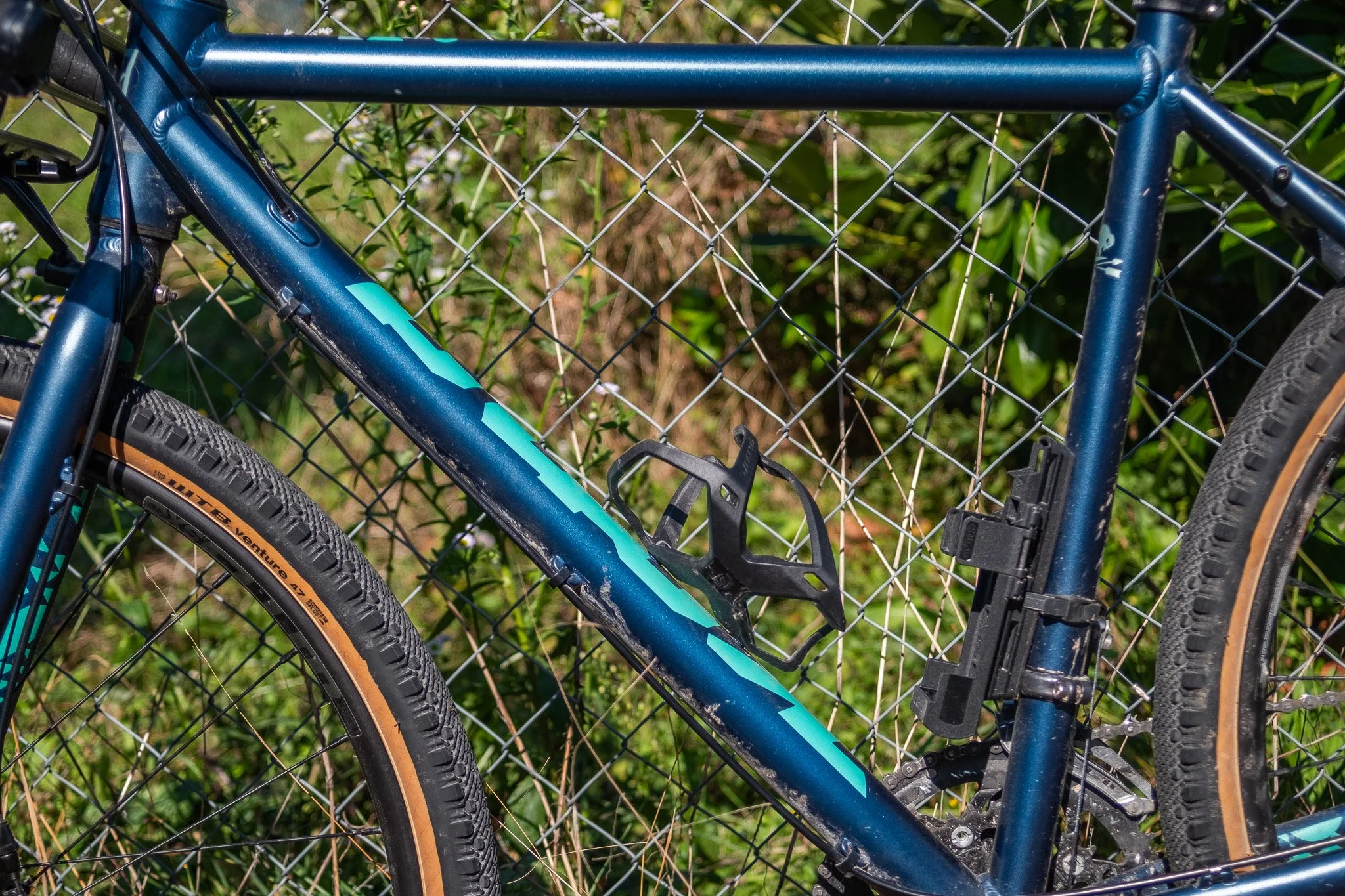 Vélo de montagne bleu attaché à une clôture métallique dans un environnement naturel
