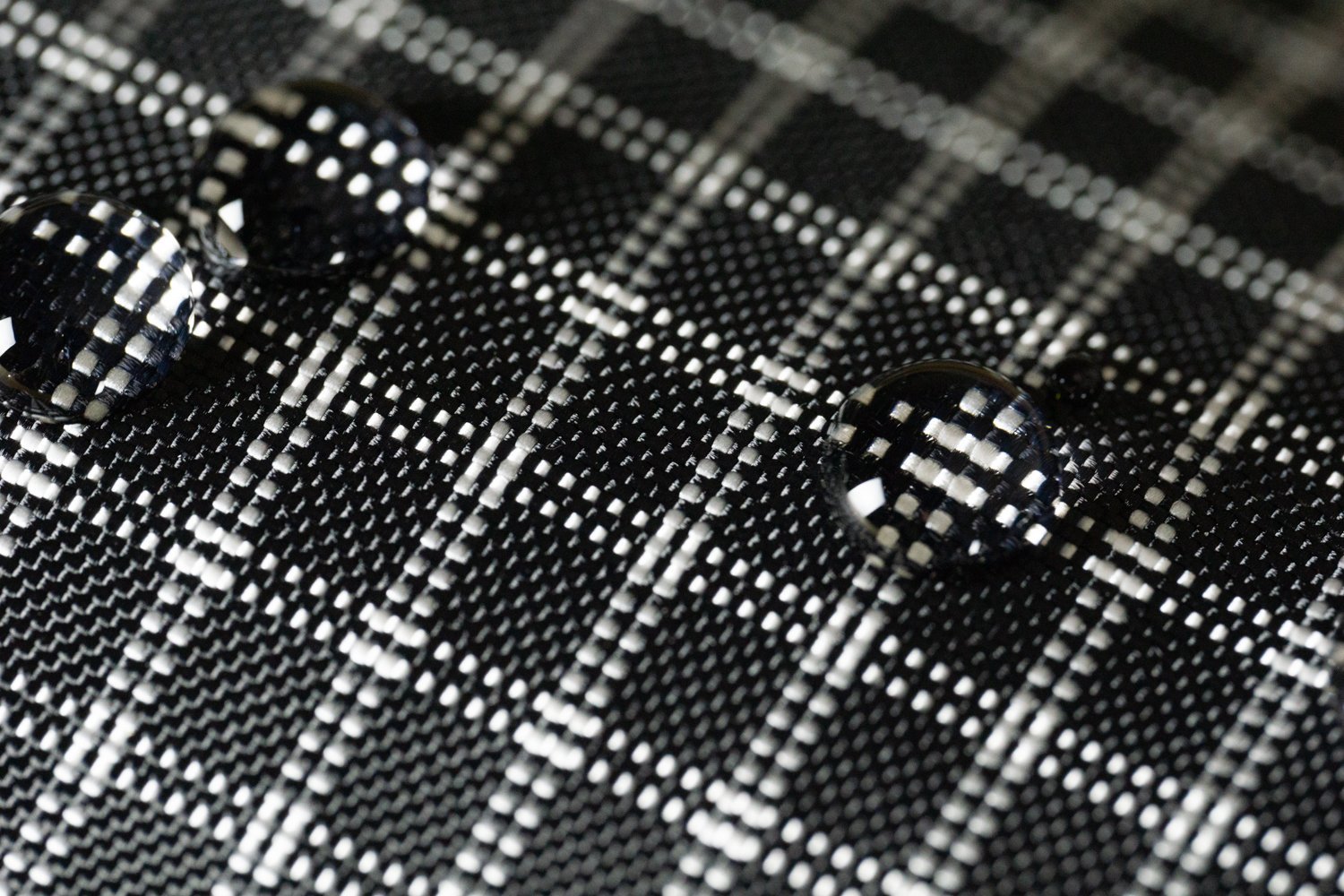 Gros plan sur un tissu en mailles noires et blanches avec deux boutons noirs.