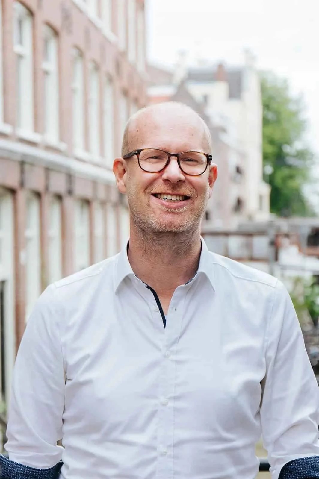 Erik Cordes wearing glasses and a white shirt standing outdoors.