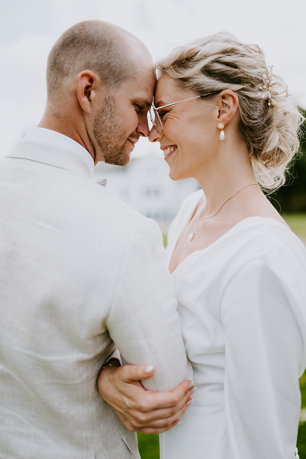 Mann og kone kless i hvit dress og hvit bryllupskjole ser romantisk på hverandre.