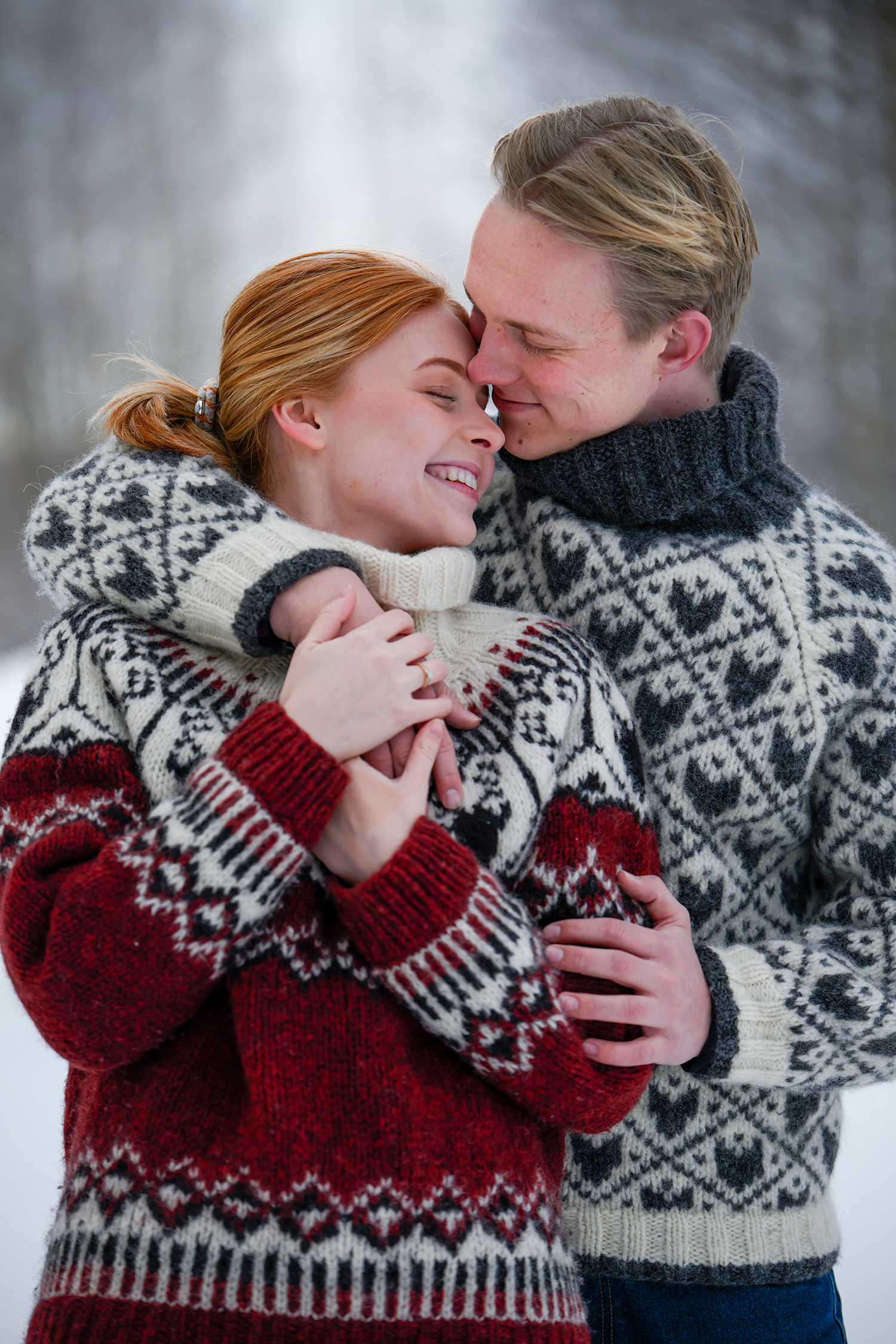 Forlovet par gir hverandre en romantisk klem i vinterland med nystrikkede gensere.