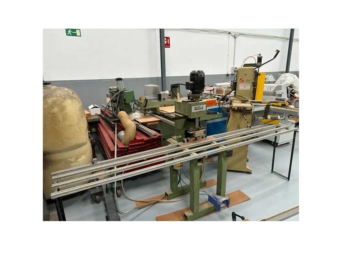 Maquinaria industrial en un taller de fabricación, incluyendo un cilindro grande, mesas de trabajo y varias máquinas eléctricas y mecánicas.