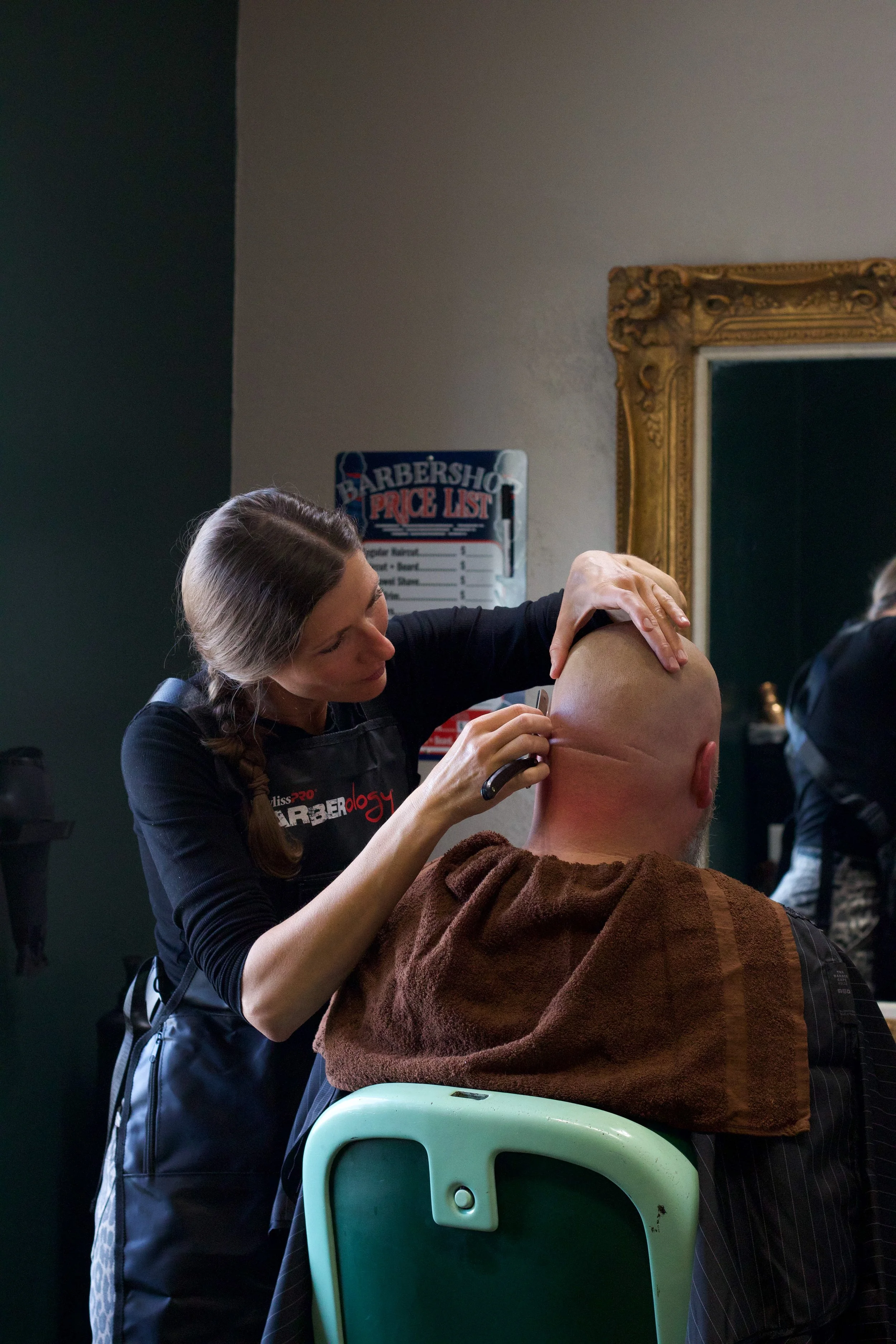 barber providing guest with straight razor shave.