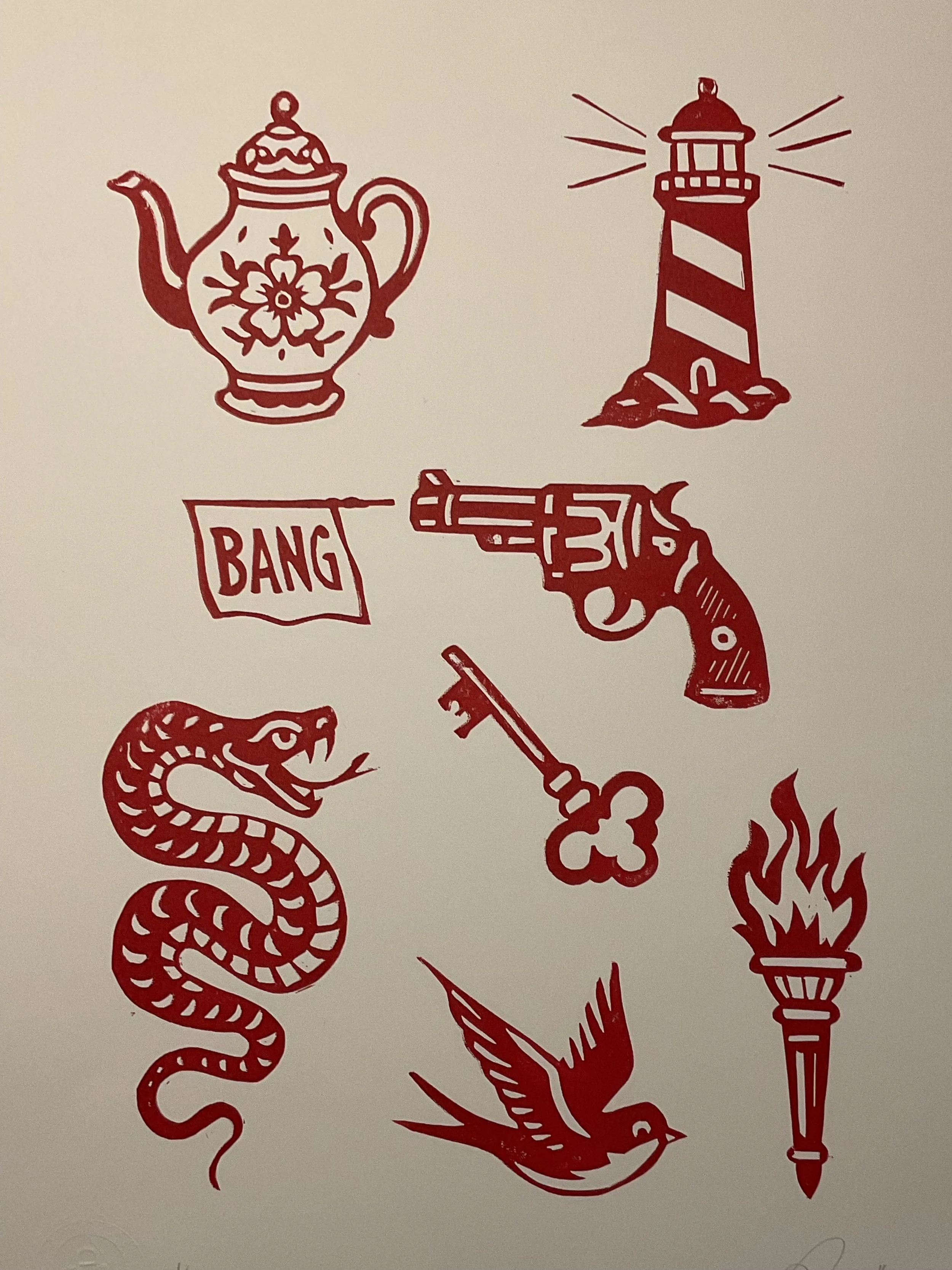 Red linocut tattoo flash print featuring a vintage teapot, lighthouse, revolver with ‘BANG’ flag, snake, key, swallow and flaming torch. Hand-carved and hand-printed by Elucidation Inc.