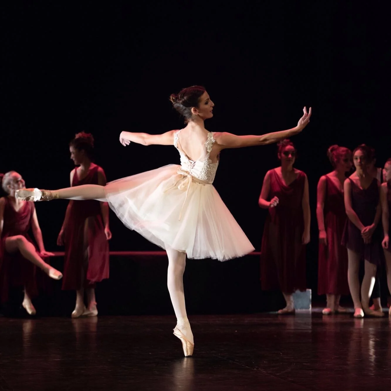 ballet dancers en répétition sur scène, une danseuse en tutu blanc en première plan