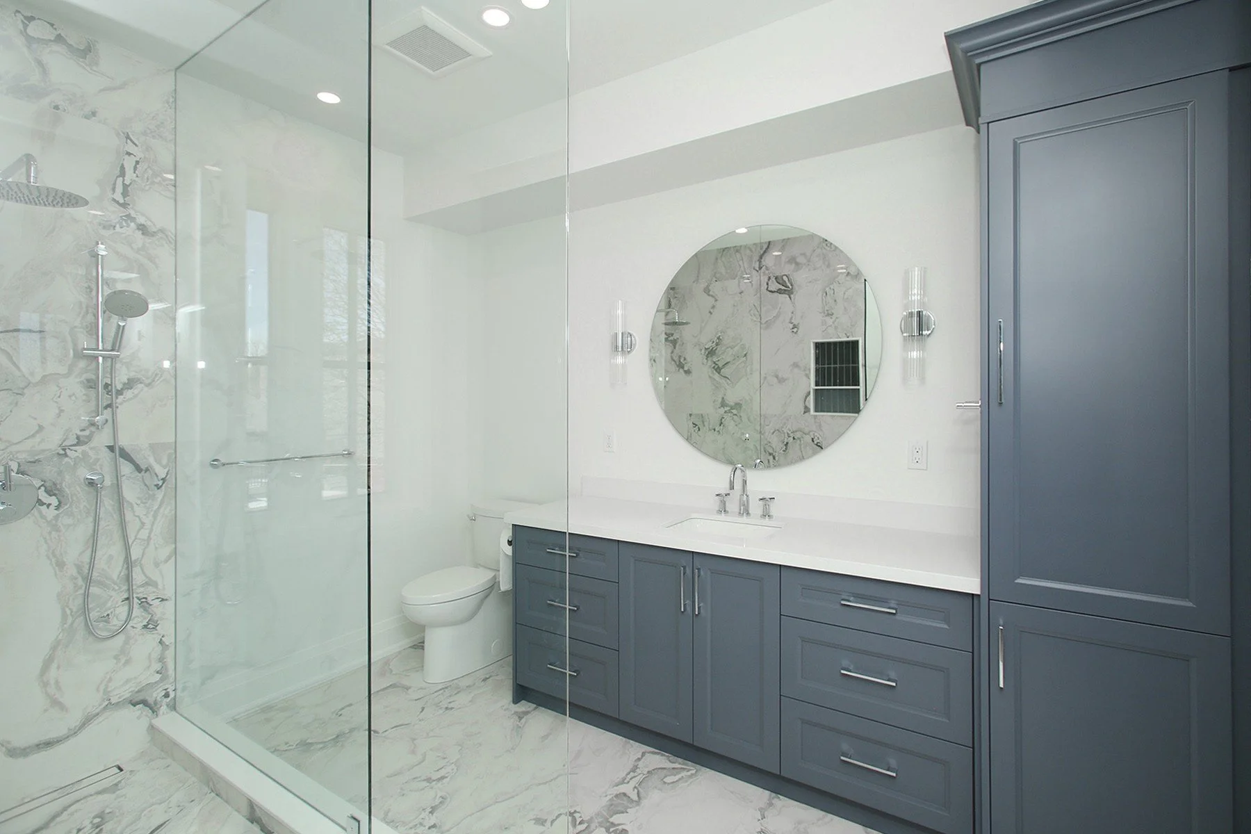 Basement apartment full bathroom with atiled flooring, dark grey cabinetry and glass shower area, created by Waterfront Homes, a design-build firm in Toronto