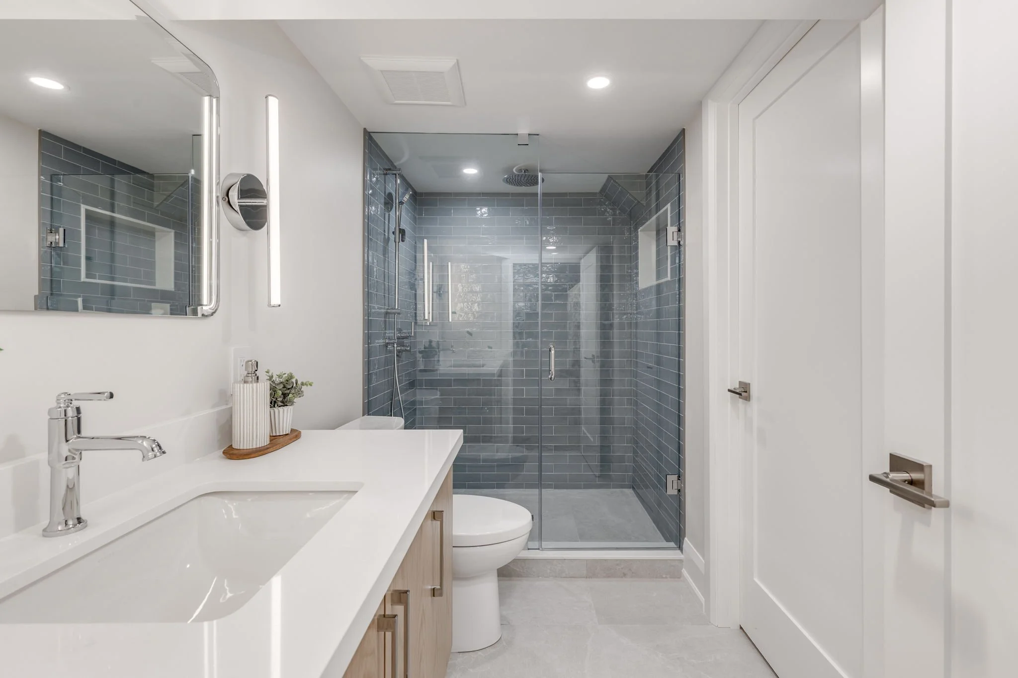 Basement apartment bathroom with a  tiled glass shower area, countertop and vanity, created by Waterfront Homes, a design-build firm in Toronto