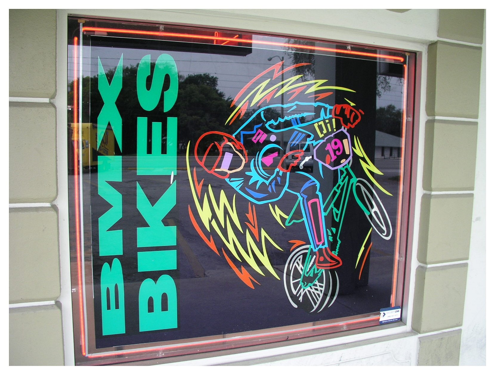 Neon sign featuring BMX biker in dynamic pose, with "BMX BIKES" text. colored window film