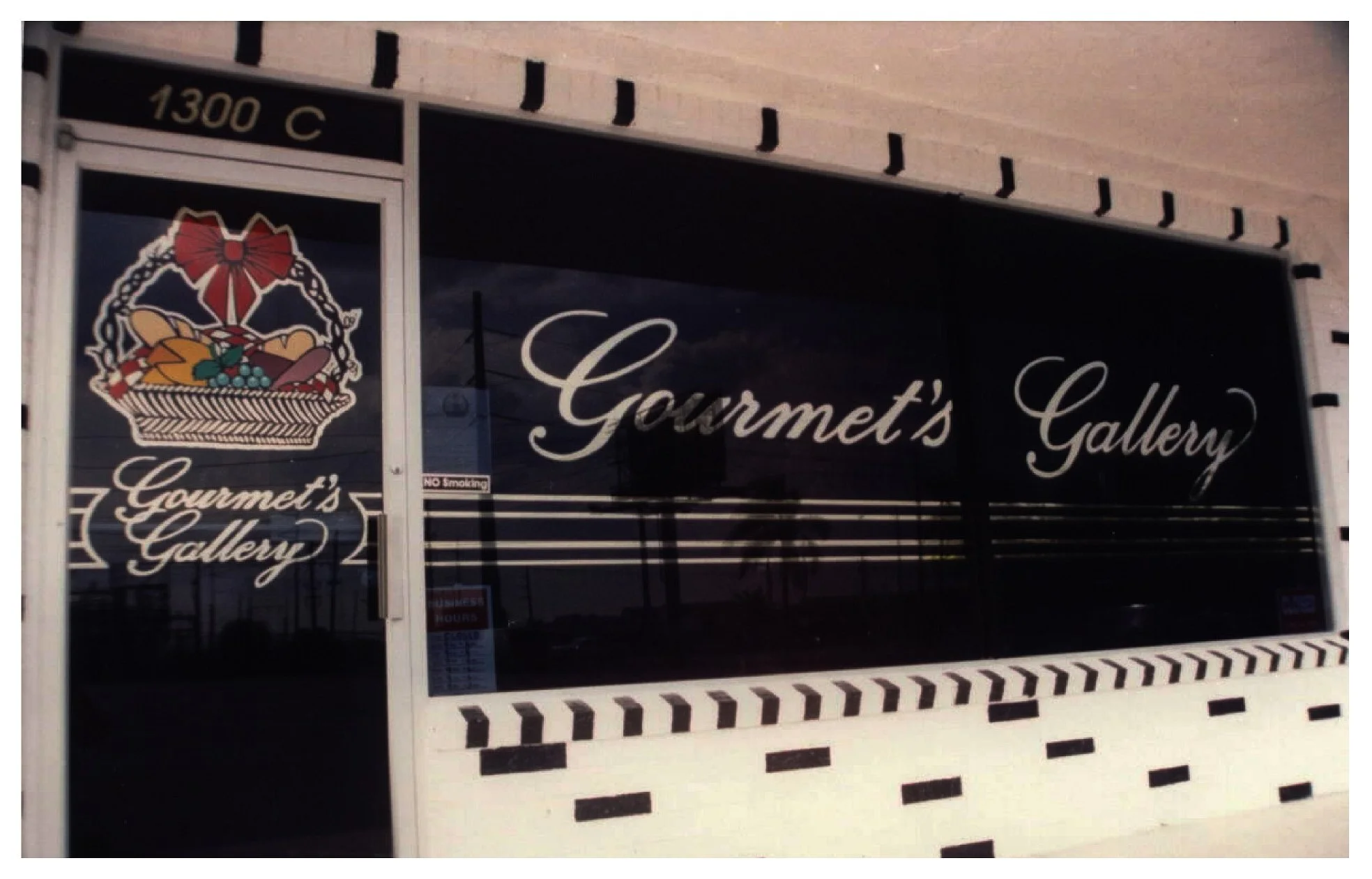 Storefront with 'Gourmet's Gallery' signage and fruit basket logo colored window film