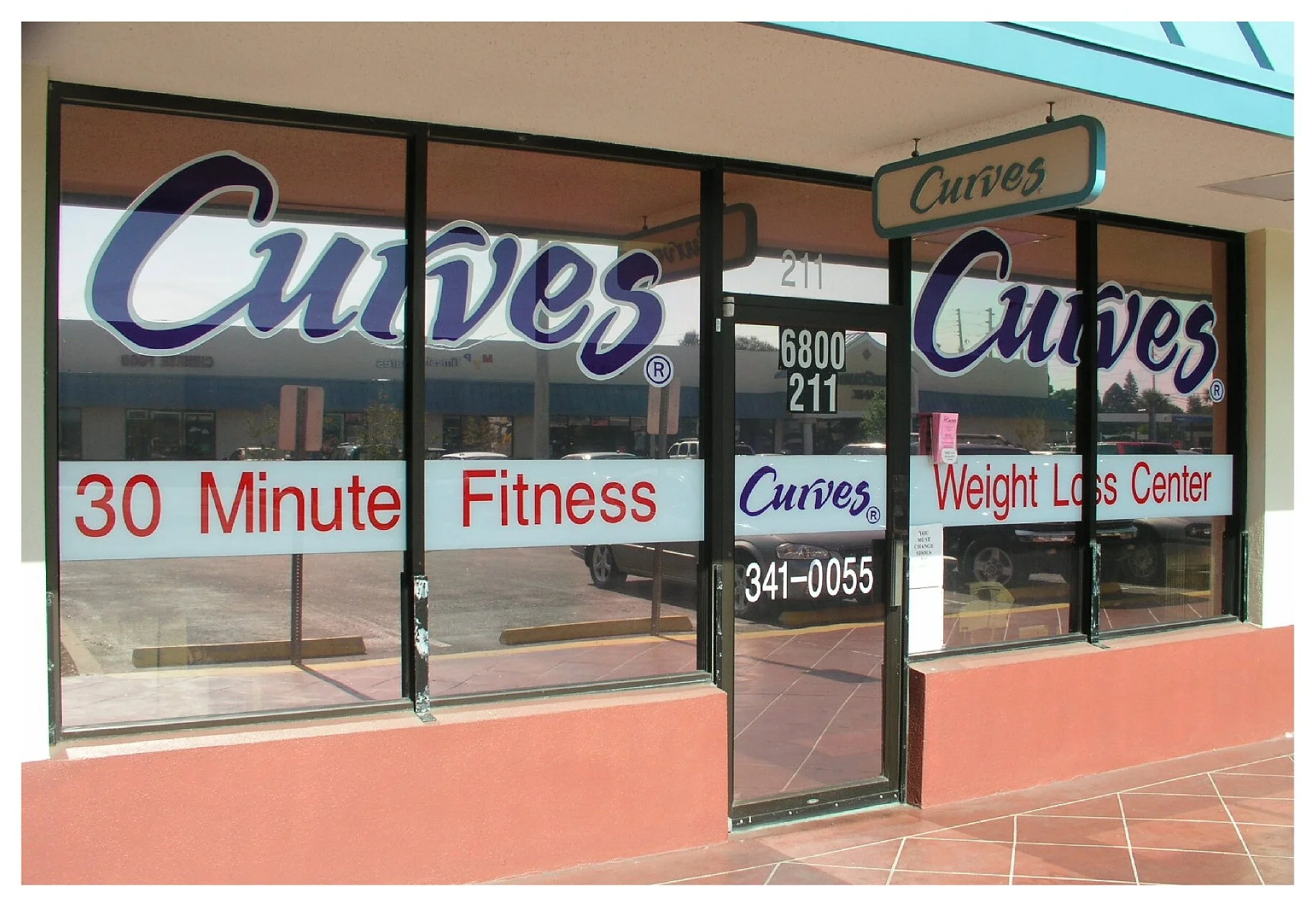 Storefront of Curves Fitness and Weight Loss Center, featuring large windows with signage promoting "30 Minute Fitness." colored window film