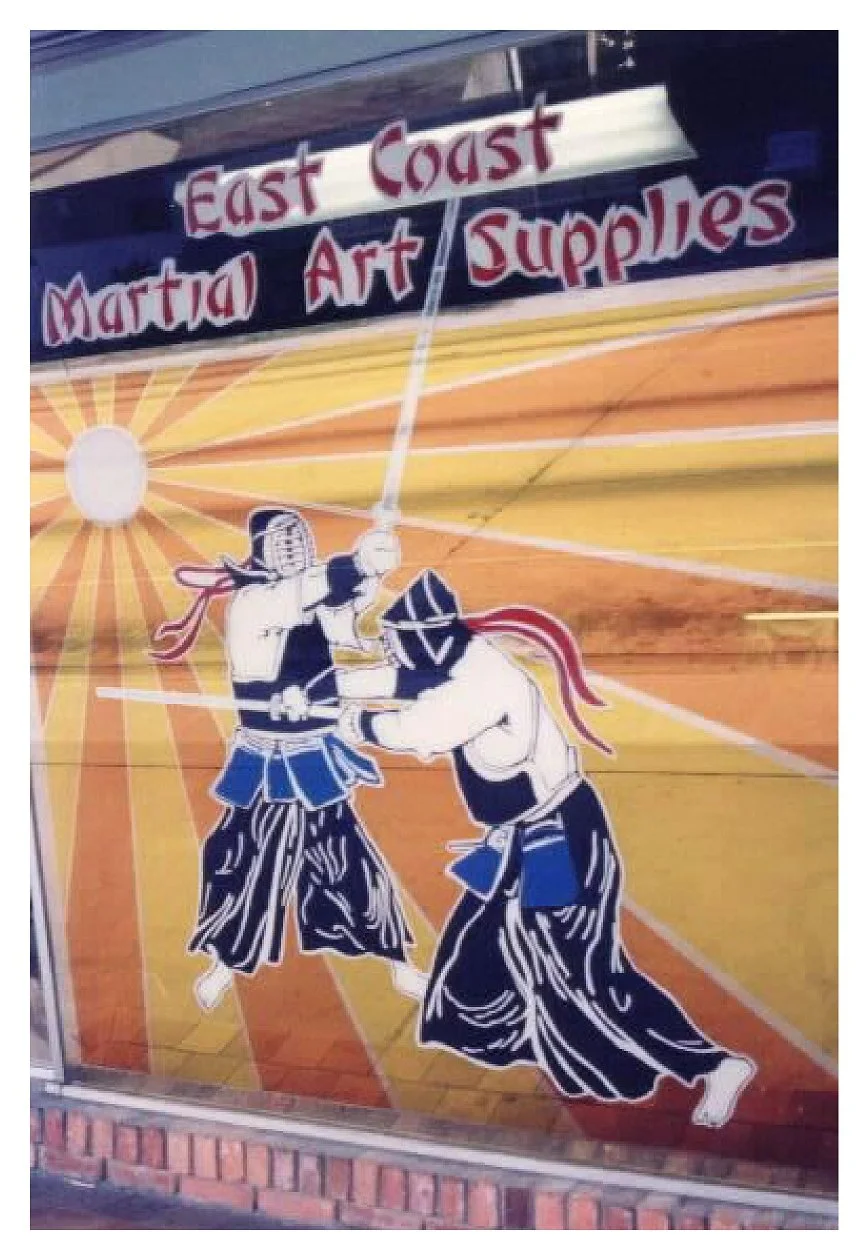 Mural of two kendo practitioners in protective armor fighting with shinai outside East Coast Martial Art Supplies. colored window film