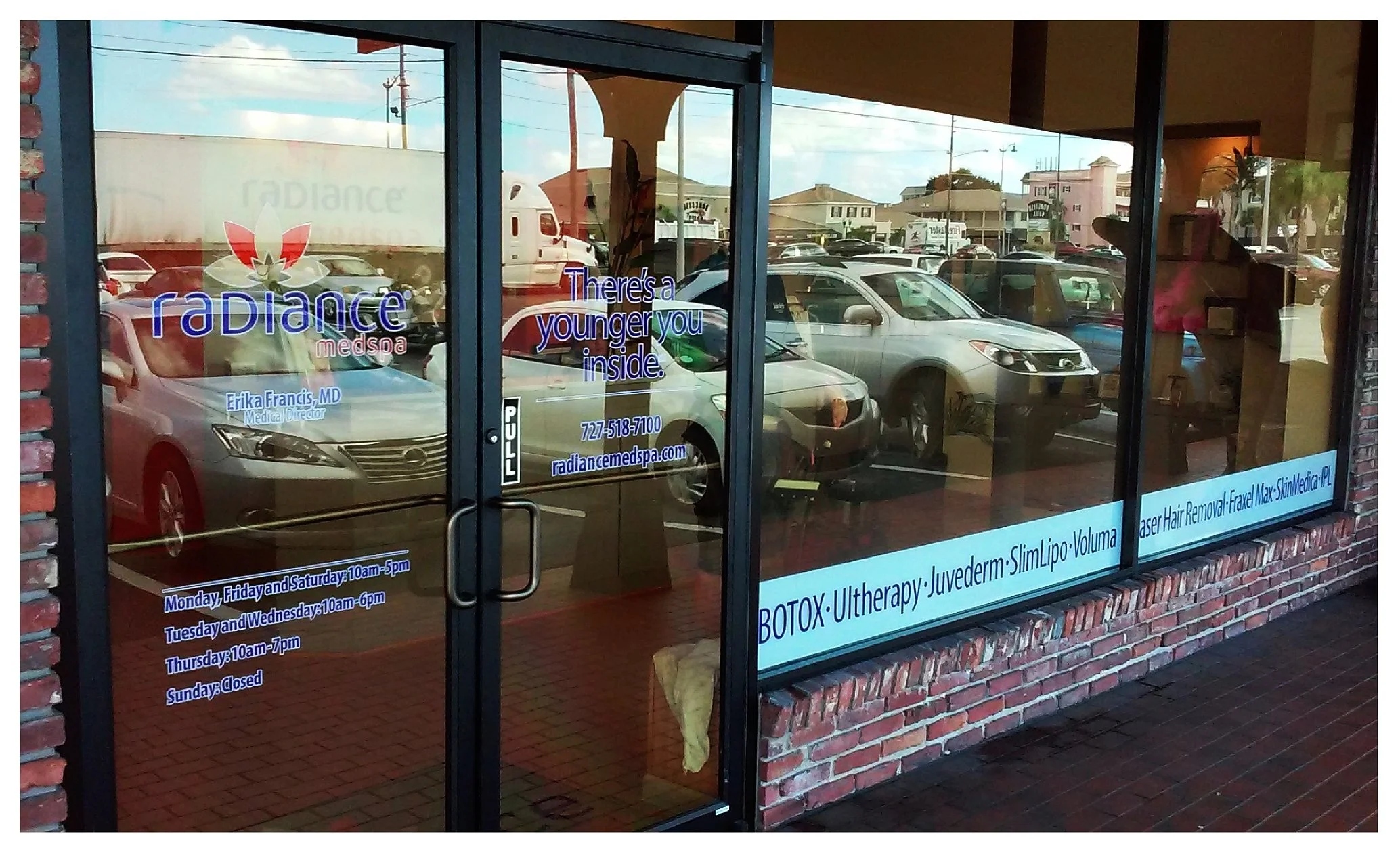 Glass storefront of Radiance Medspa with reflection of parking lot and cars colored window film