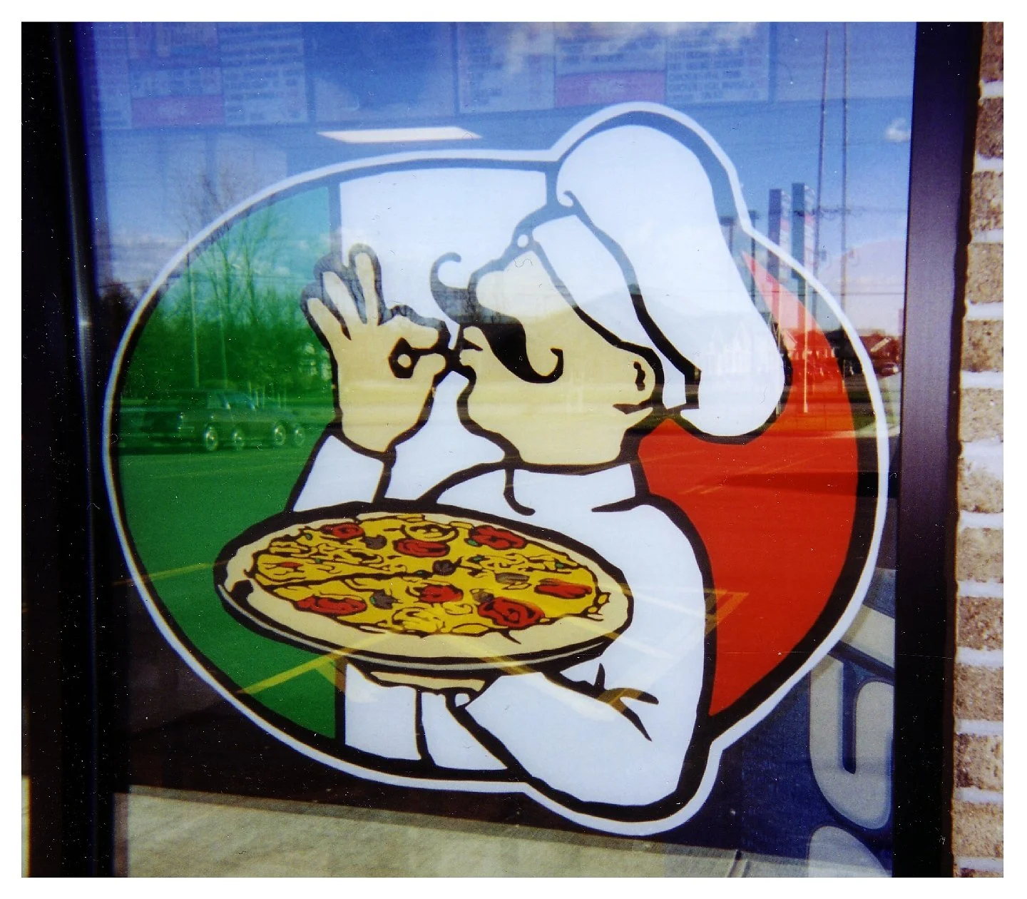Cartoon chef holding pizza, making "okay" gesture, displayed on a window with Italian flag colors. colored window film