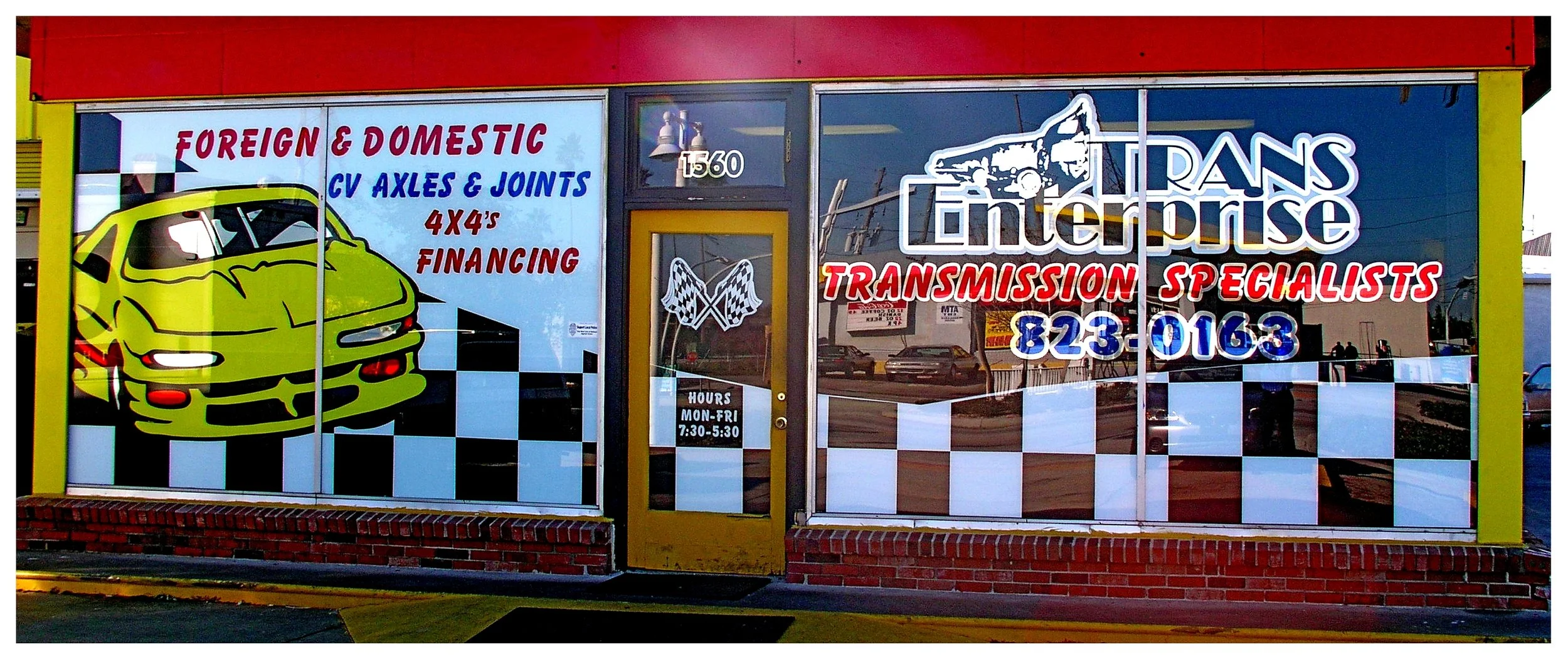 Auto repair shop front with signs displaying services for foreign and domestic vehicles, CV axles, joints, and financing options. colored window film