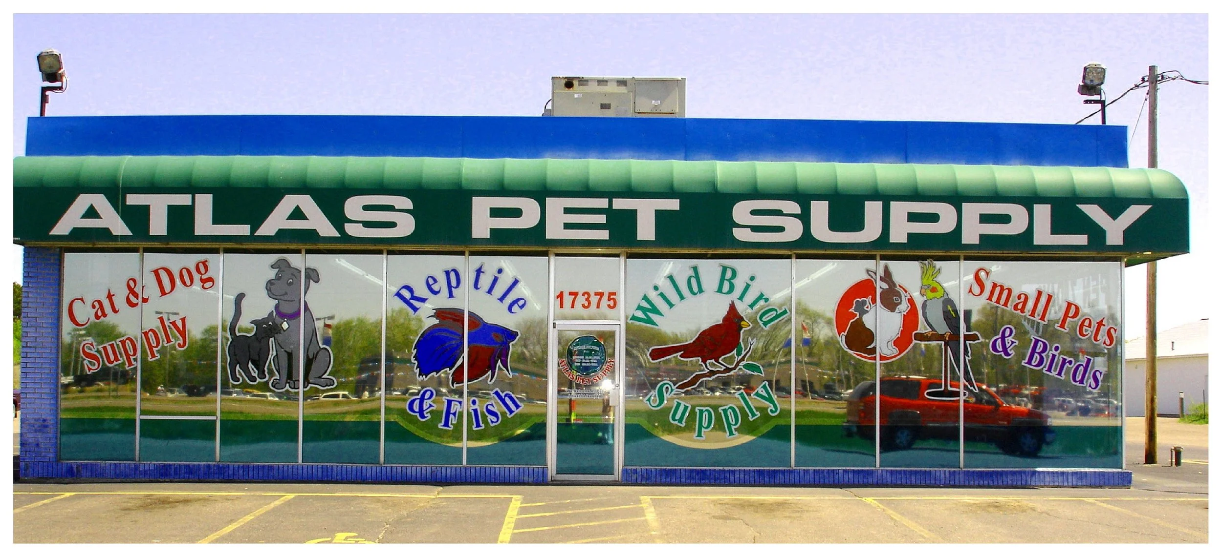 Atlas Pet Supply store exterior with colorful graphics and text advertising supplies for cats, dogs, reptiles, fish, wild birds, and small pets. colored window film