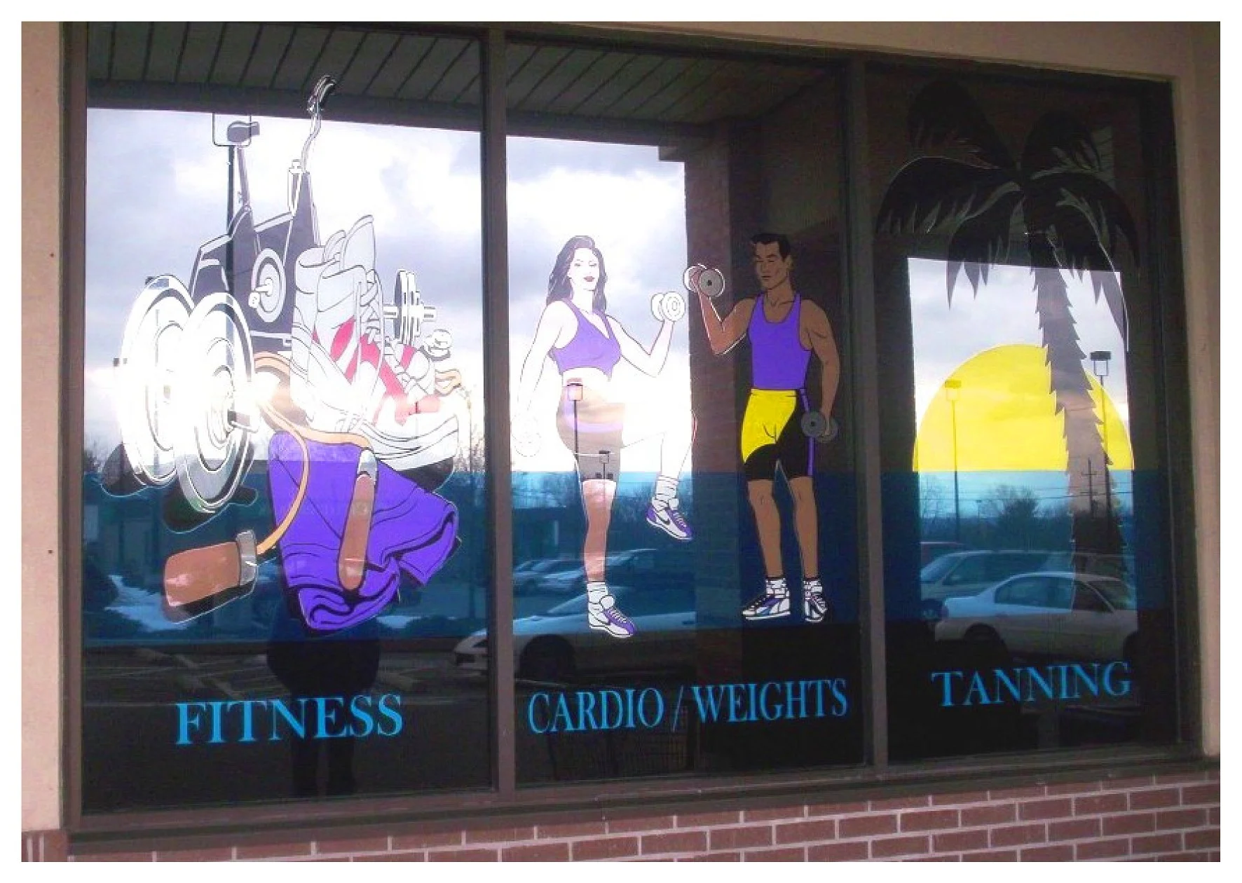 Fitness center window decals showing fitness equipment, a woman exercising, a man lifting weights, and a sunset with palm tree. Text labels "FITNESS," "CARDIO/WEIGHTS," "TANNING." colored window film
