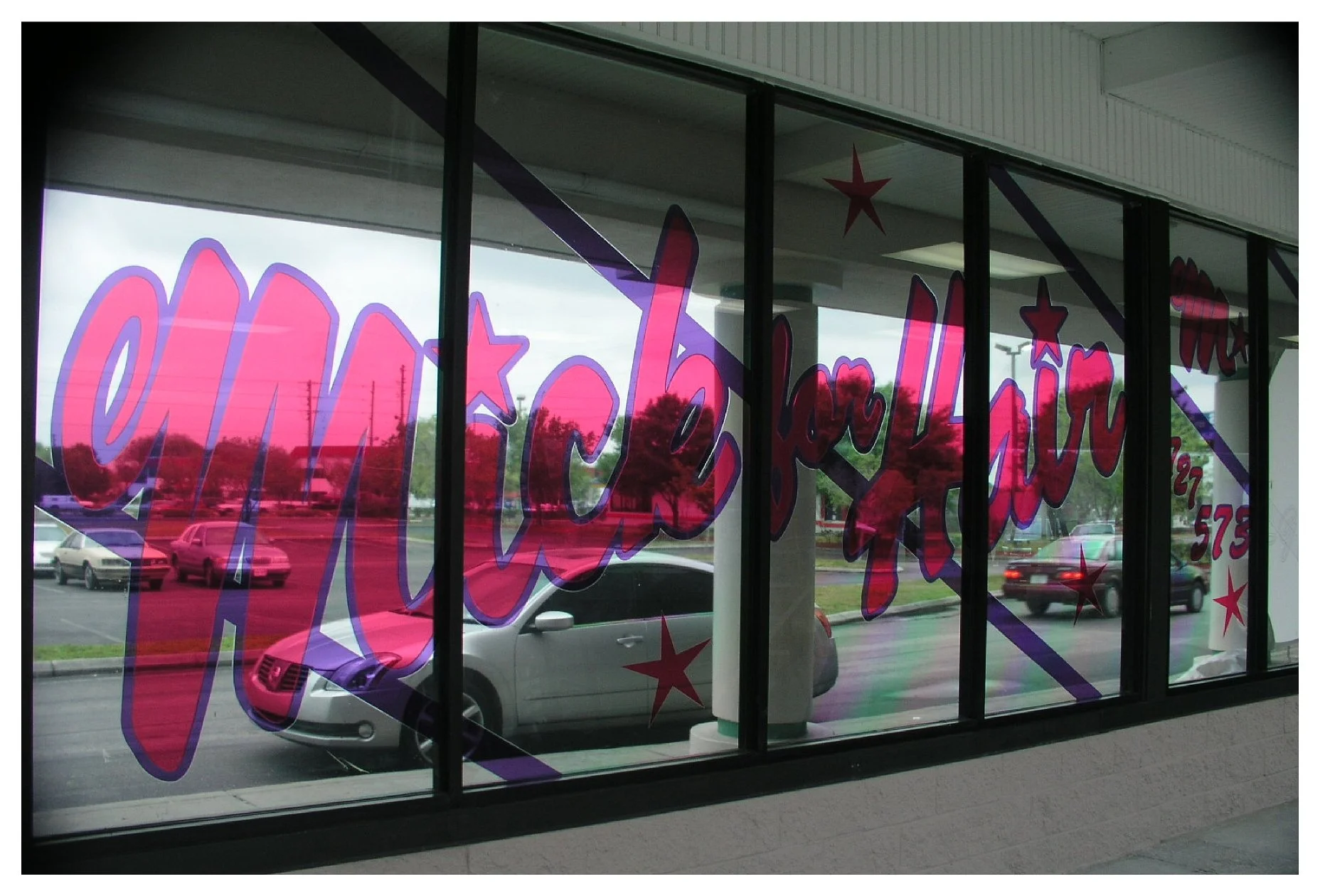 Storefront window with "Mick for Hair" lettering and star decorations colored window film
