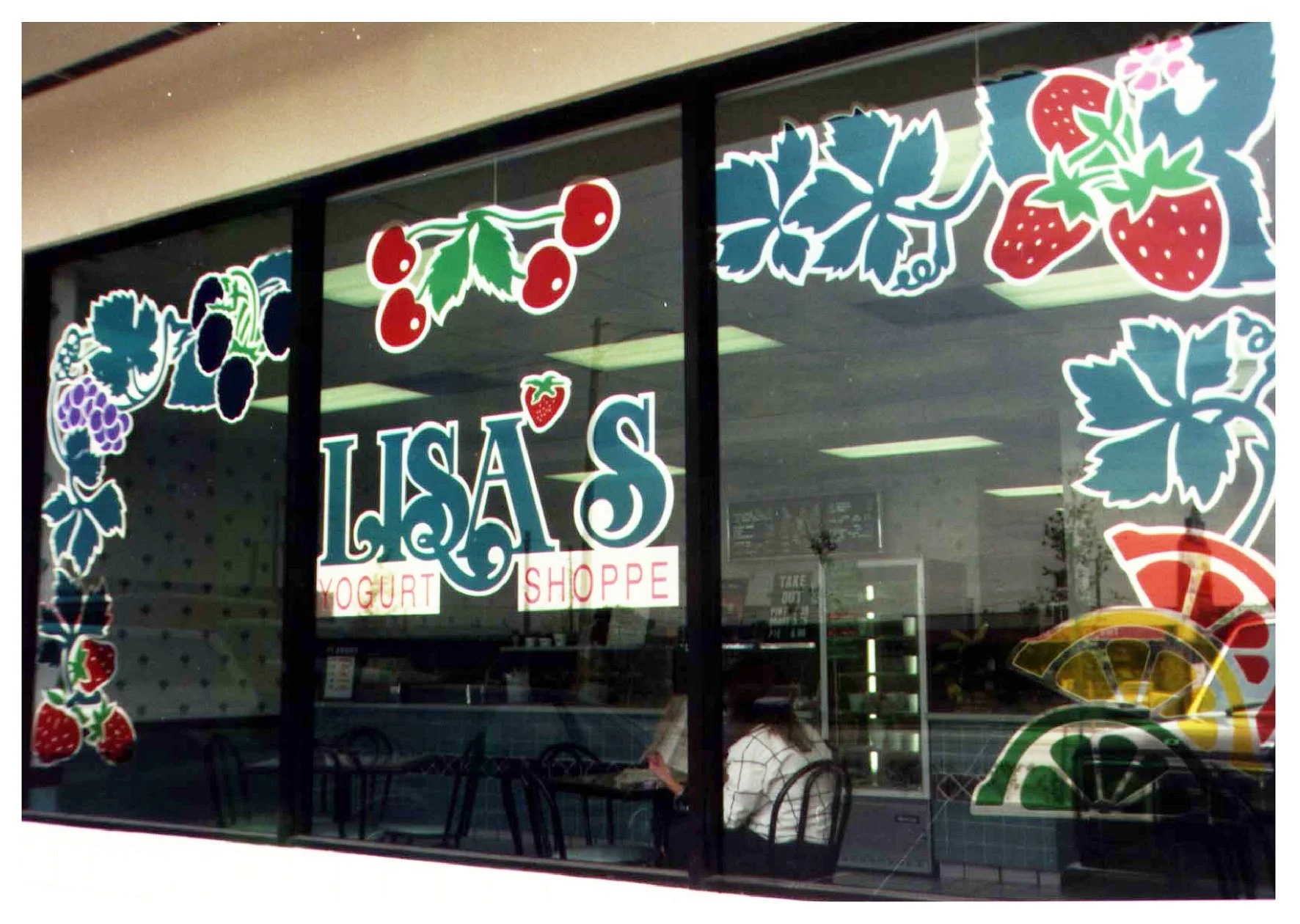 Front window of Lisa's Yogurt Shoppe with colorful fruit decorations and people inside colored window film