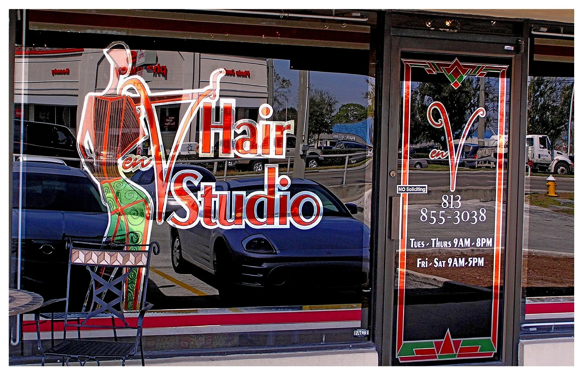 Hair studio storefront with vibrant signage and business hours displayed on the door. colored window film