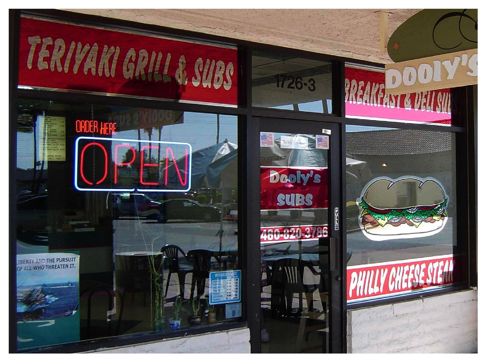 Exterior of a deli named Dooly's Subs with an open sign and Philly cheesesteak graphic. colored window film