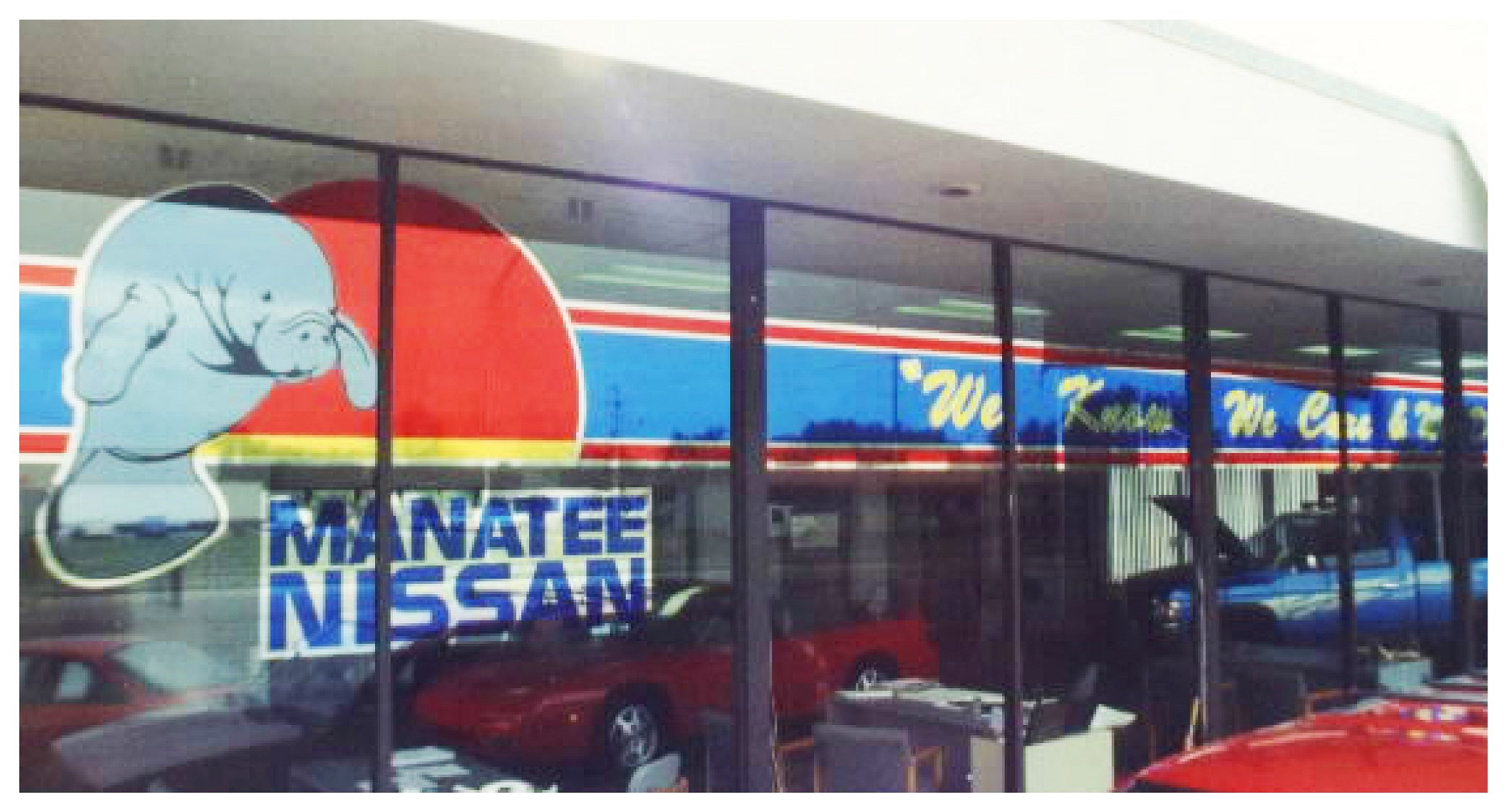 Car dealership with "Manatee Nissan" sign and manatee graphic on window.
