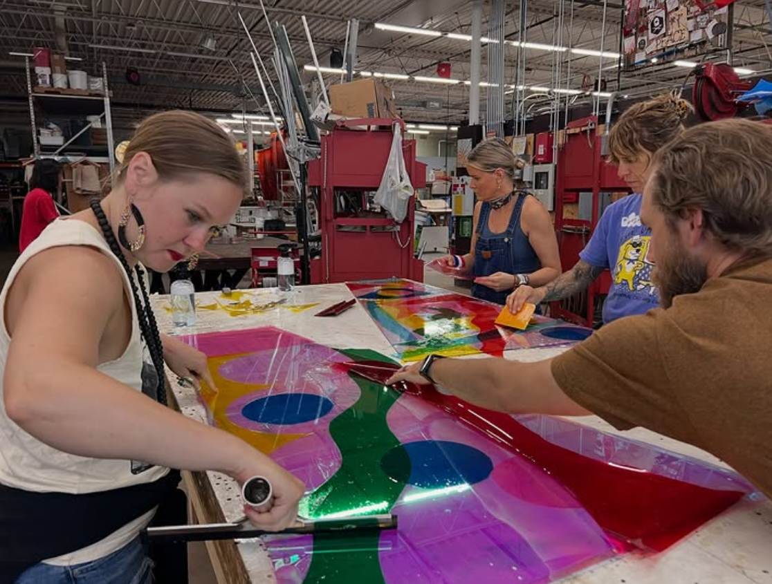 People working on colorful stained glass panels in a workshop. colored window film