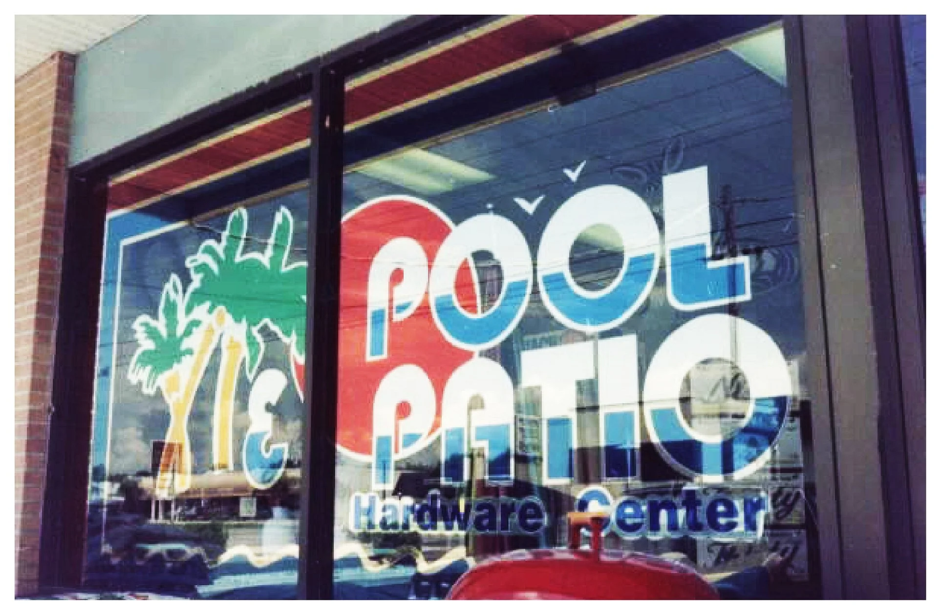 Shop window sign for 'Pool & Patio Hardware Center' with palm tree graphics. colored window film