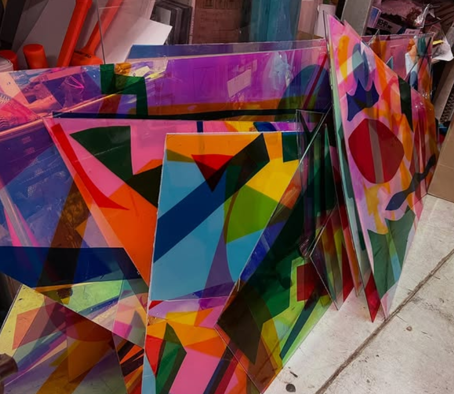 Colorful, abstract geometric artwork leaning against a wall, with various bright and vivid shapes and colors.  colored window film