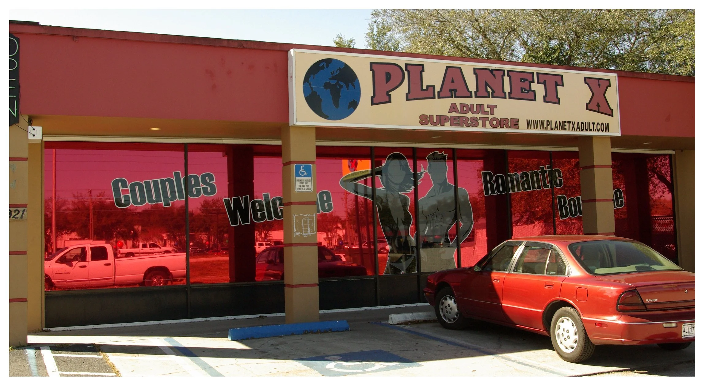Exterior of Planet X Adult Superstore with red windows and a parked car. colored window film