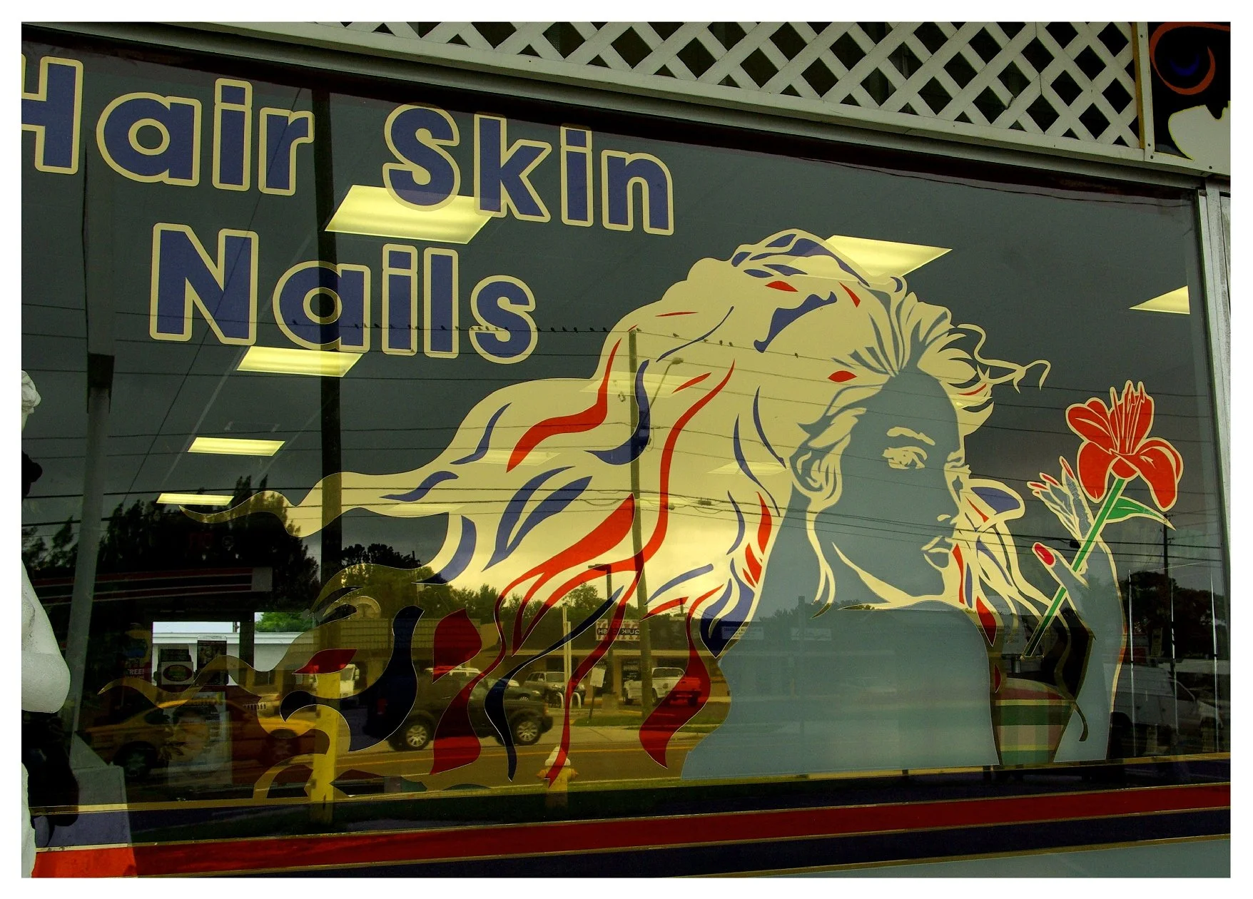Shop window with 'Hair Skin Nails' text, illustration of woman with colorful hair holding a red flower. colored window film
