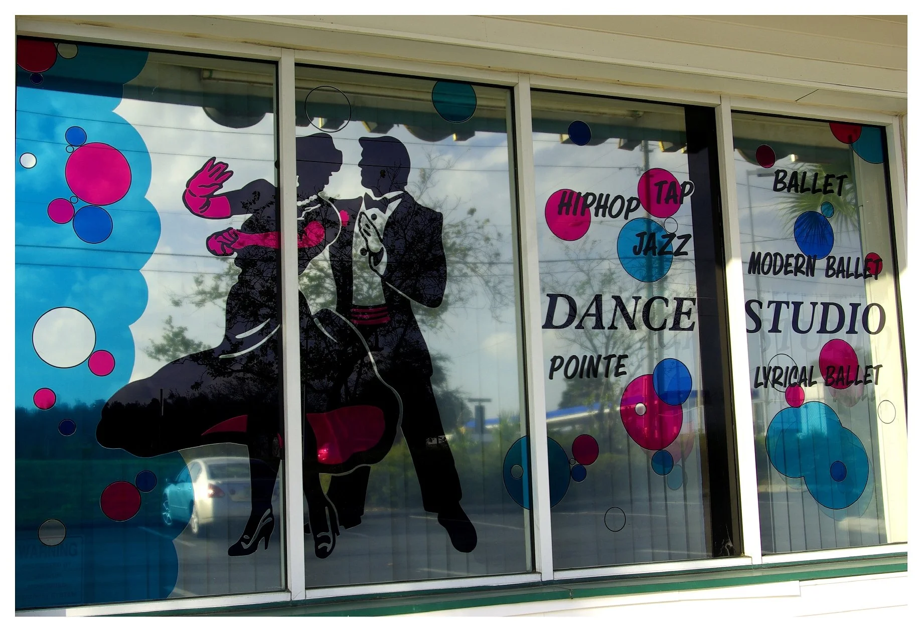 Dance studio window with a silhouette of a dancing couple and words like hip-hop, tap, jazz, ballet, modern ballet, lyrical ballet, pointe. colored window film