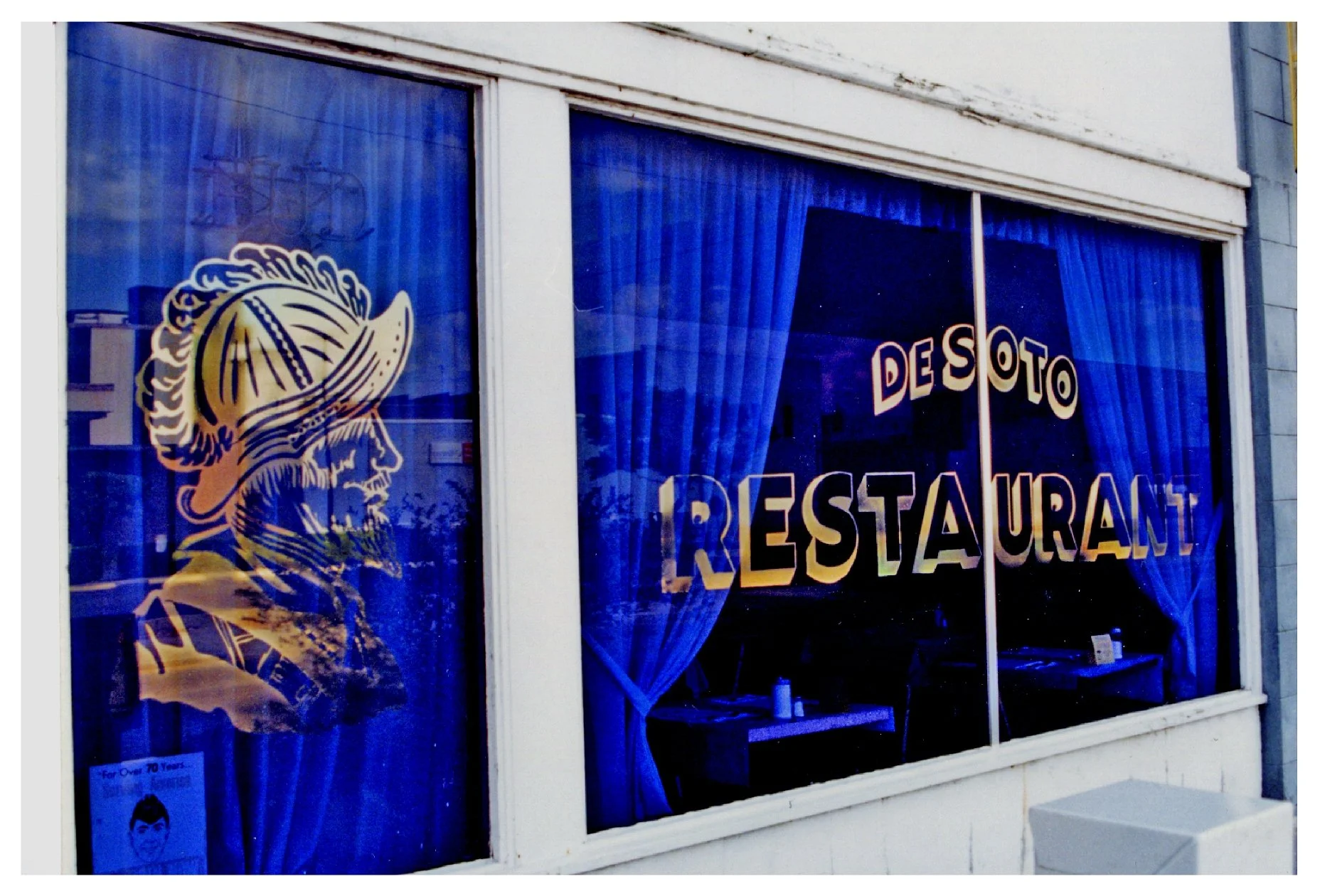De Soto Restaurant window with blue curtains and golden silhouette colored window film