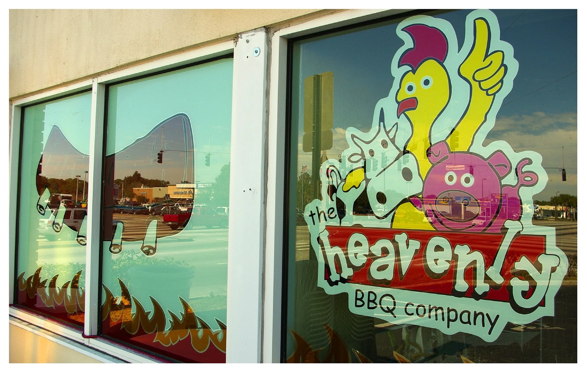 BBQ restaurant window with cartoon chicken, cow, pig illustration and the words 'The Heavenly BBQ Company'