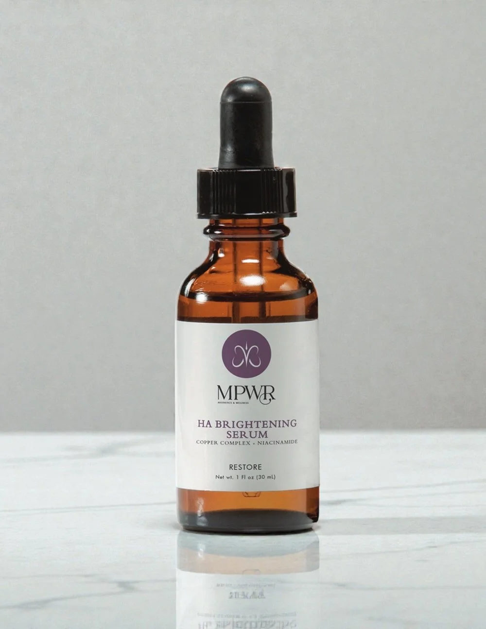 Amber glass bottle with dropper cap labeled MPWR HA Brightening Serum for skincare.