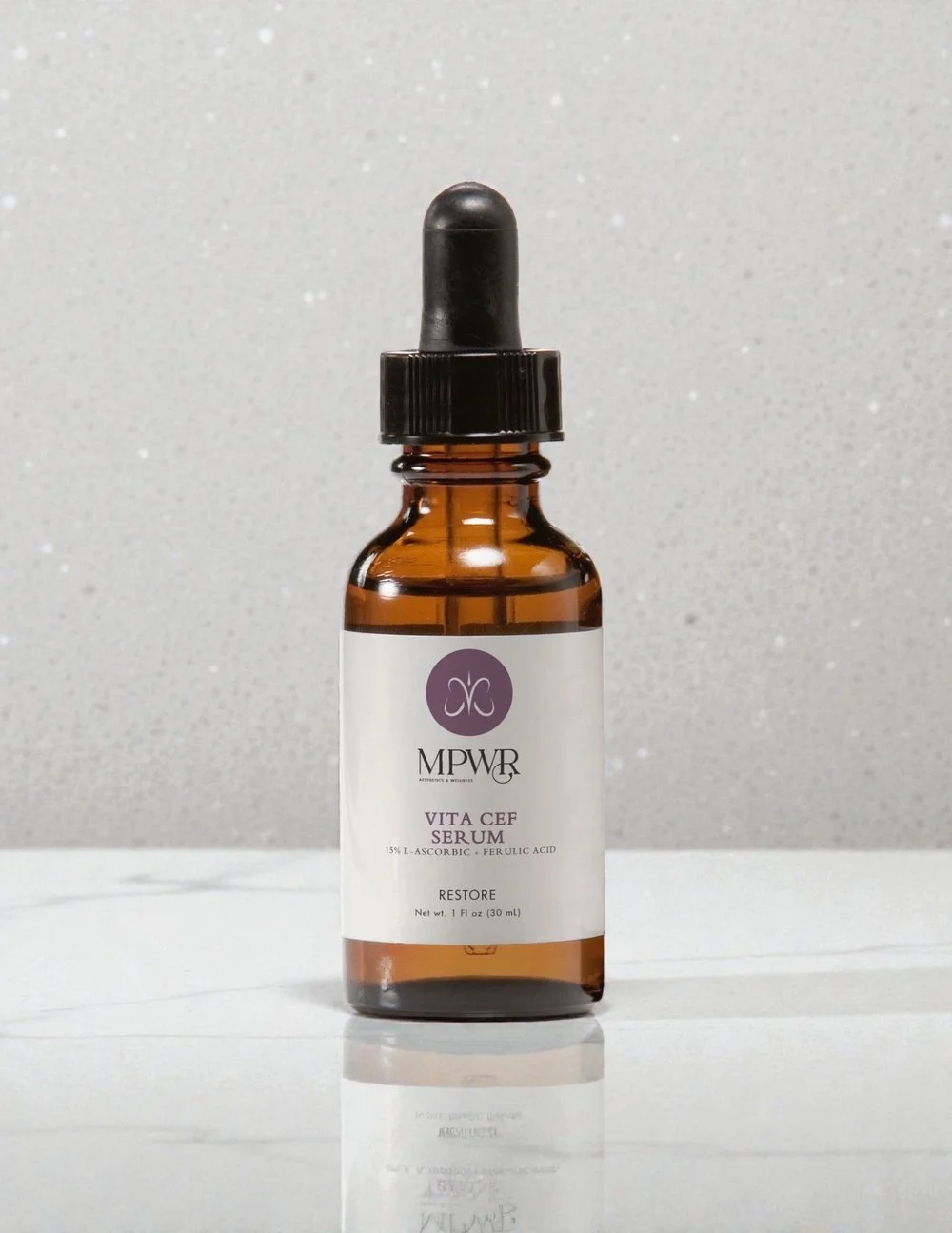 Small amber glass bottle with black dropper cap labeled MPWR Vita CEF serum, containing 15% L-ascorbic and ferulic acid, against a white background.