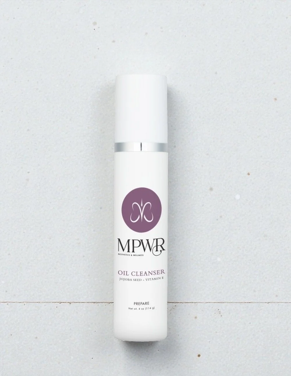 White bottle of MPWR Oil Cleanser with Jojoba Seed and Vitamin E, with branding and product details labeled on the front.