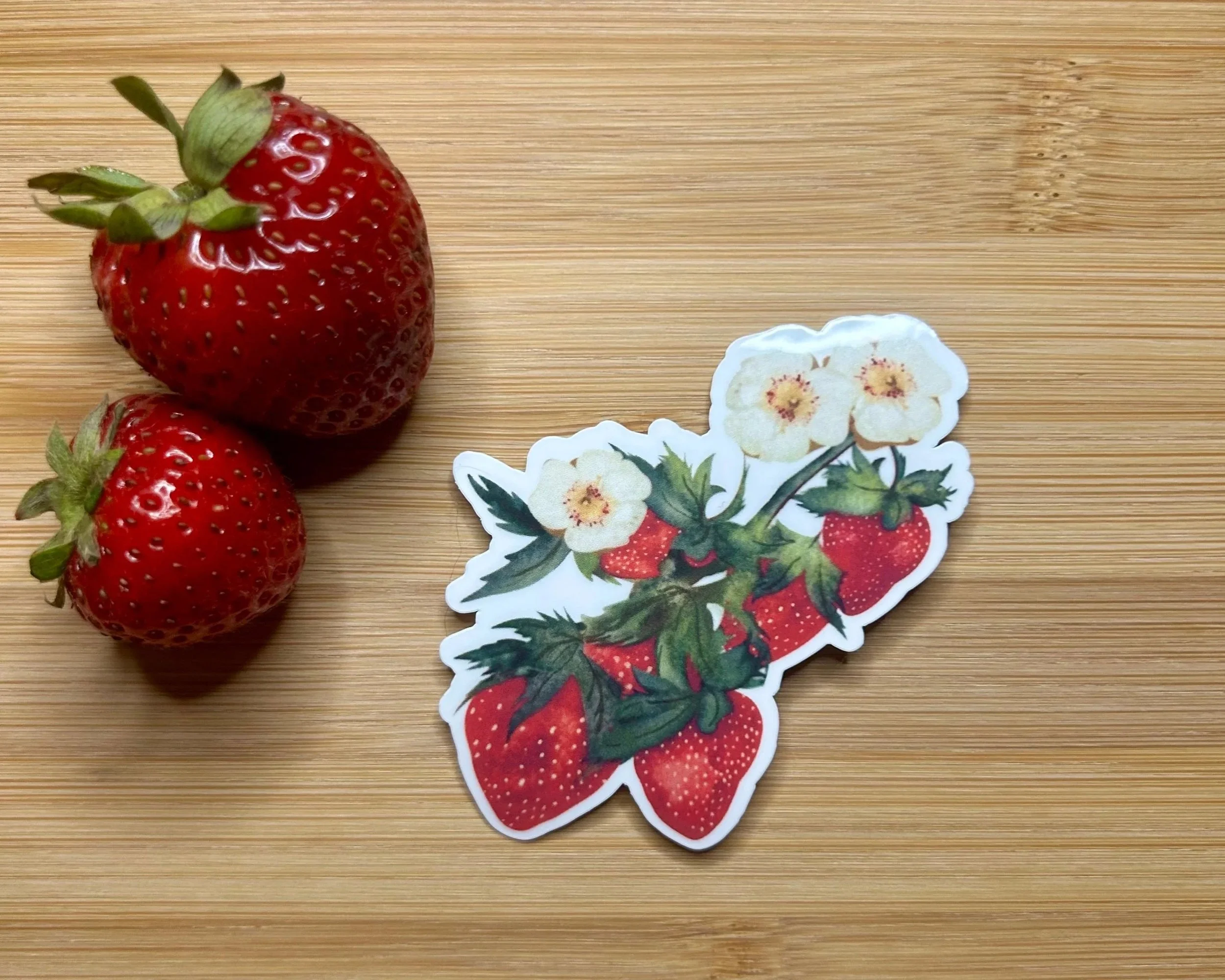 Hand-illustrated strawberry bunch die-cut sticker featuring ripe red strawberries, cream blossoms and leafy green stems.