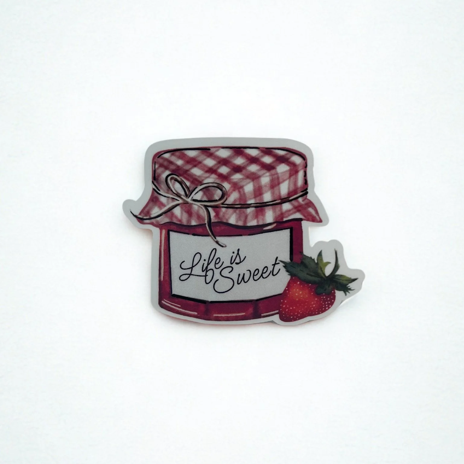 Hand-illustrated Life Is Sweet strawberry jam jar die-cut sticker with pink gingham lid and ripe strawberry.