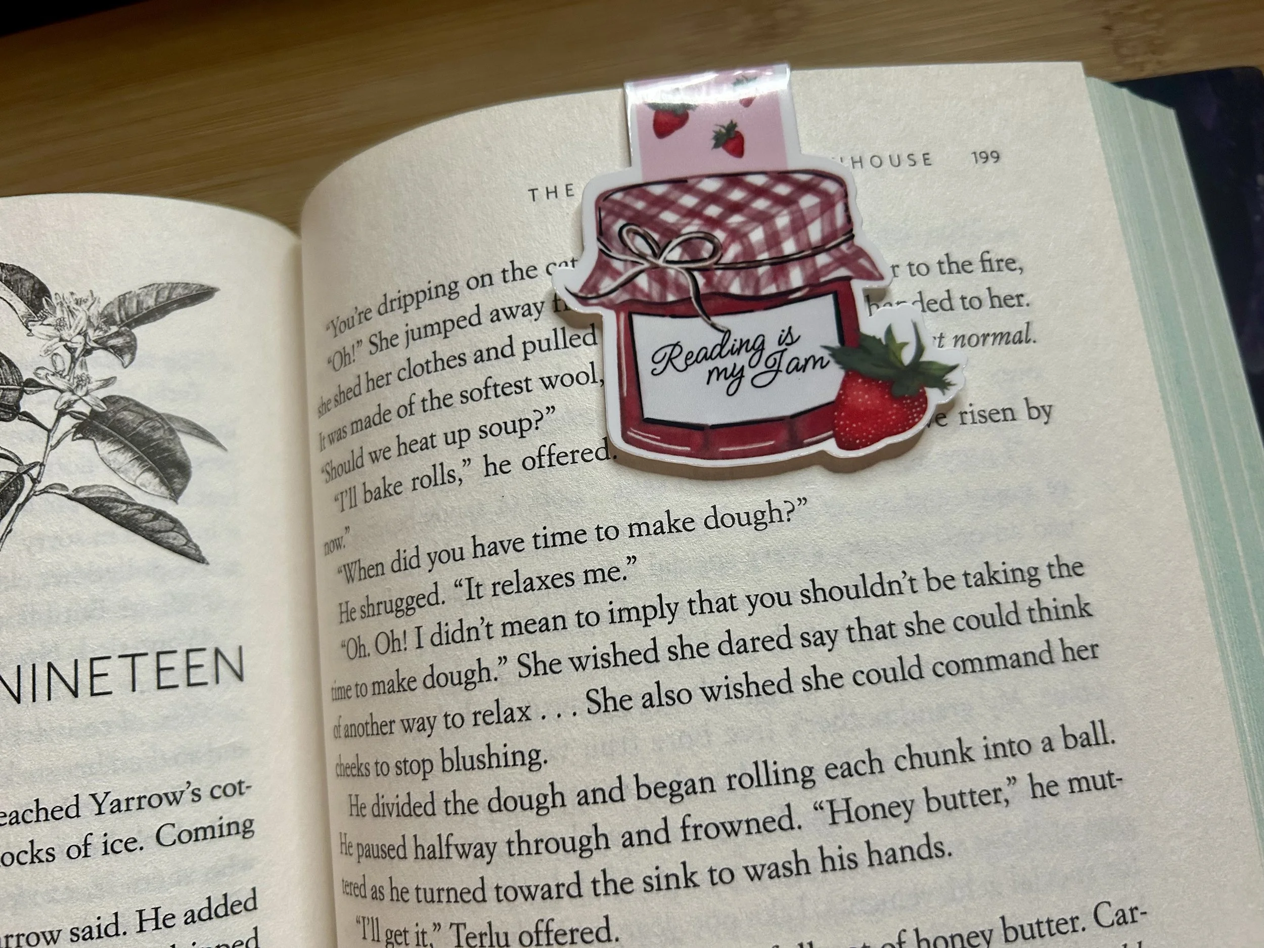 Handcrafted Reading Is My Jam strawberry magnetic bookmark holding a page in an open book from the Gather Strawberry Summer Collection shown in place on book.