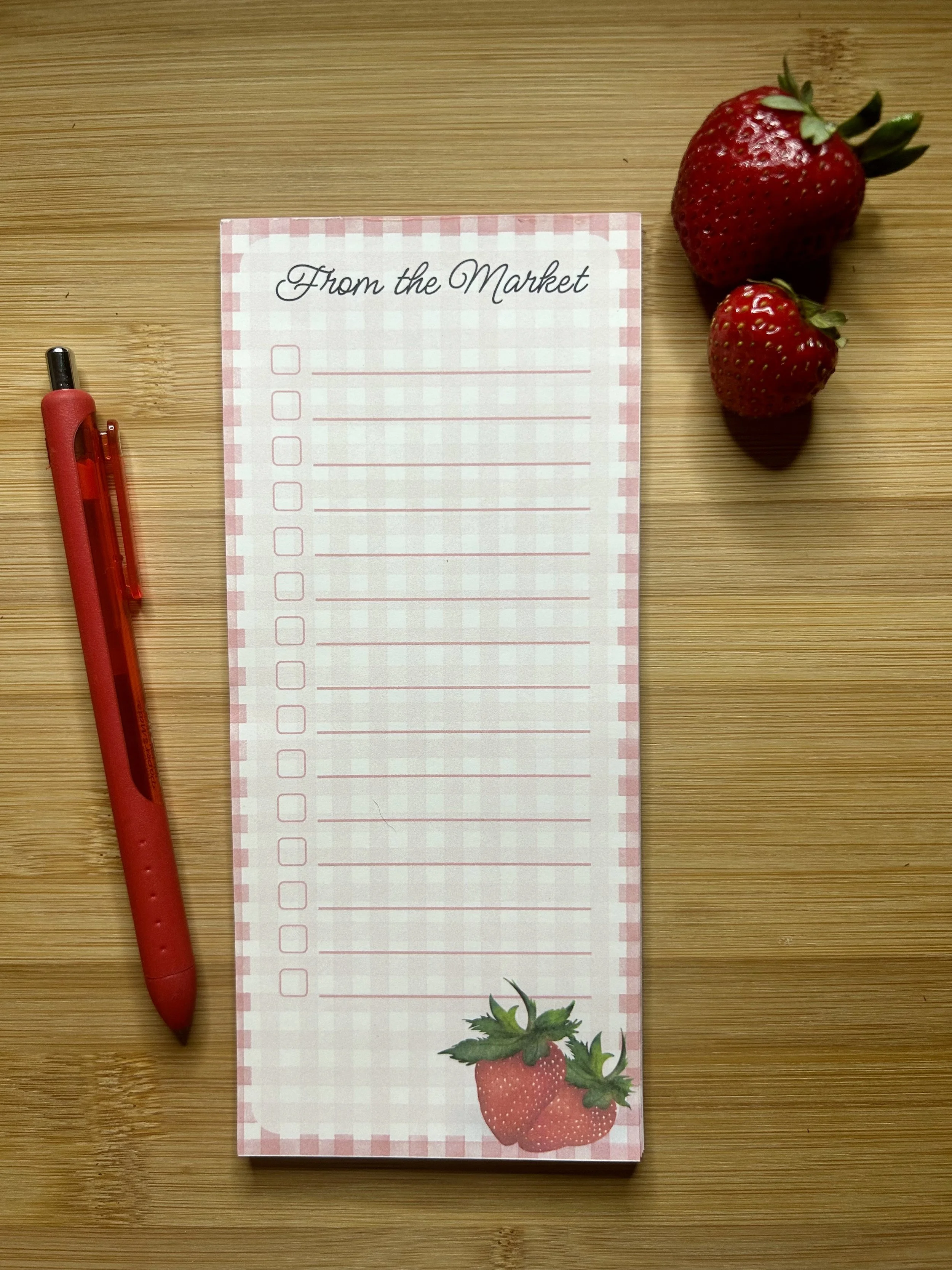 Handmade strawberry magnetic grocery list pad with pink gingham pattern, checkboxes, writing lines and hand-illustrated strawberries.
