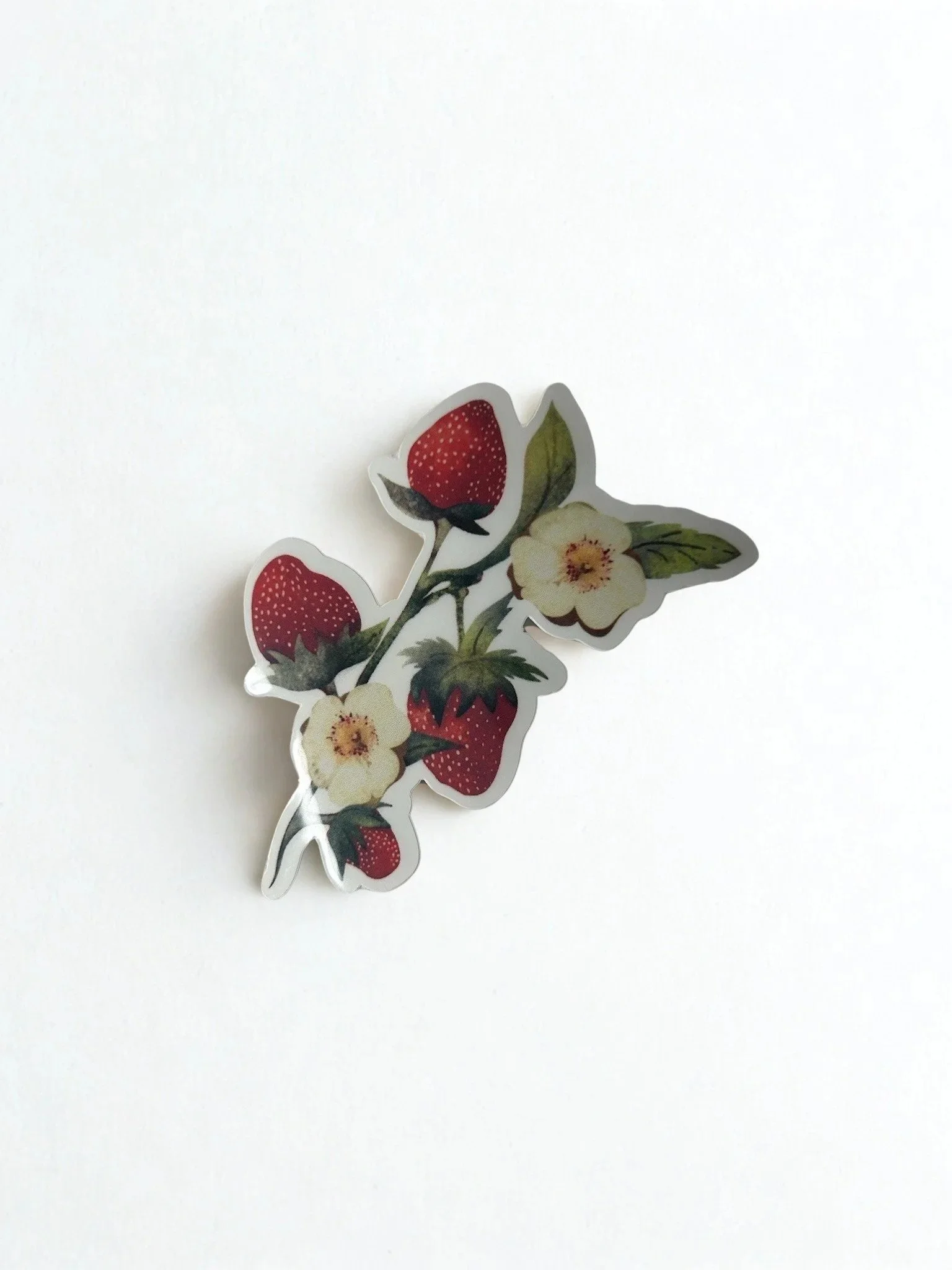 Hand-illustrated strawberry blossom die-cut sticker featuring ripe red strawberries, cream blossoms and green leaves.