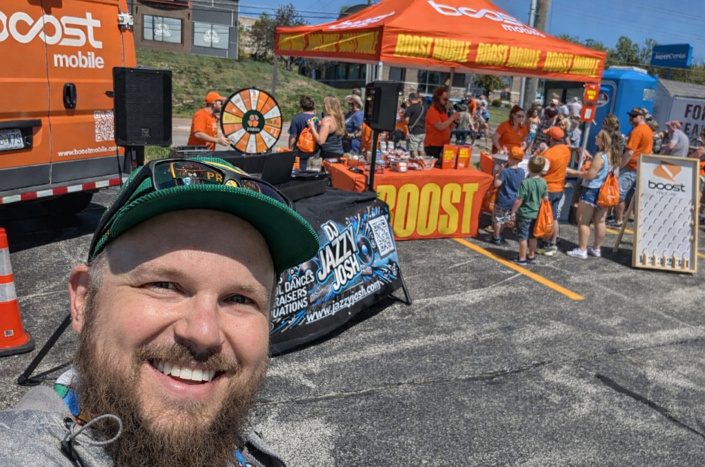 DJ Jazzy Josh hosting a live outdoor promotional event with music, crowd interaction, and branded entertainment setup for Boost Mobile.