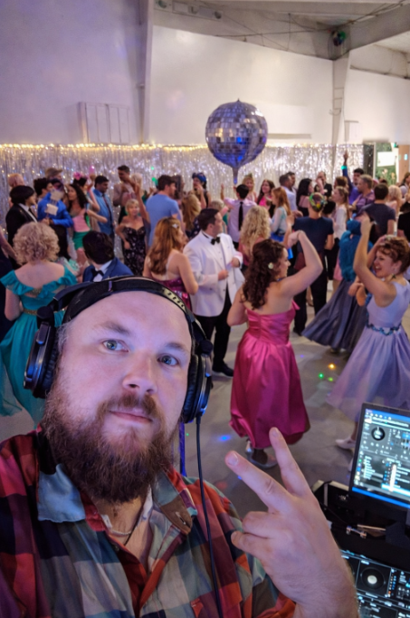 DJ Jazzy Josh performing at an 80s-themed corporate Christmas party with a packed dance floor, retro decorations, and guests celebrating.