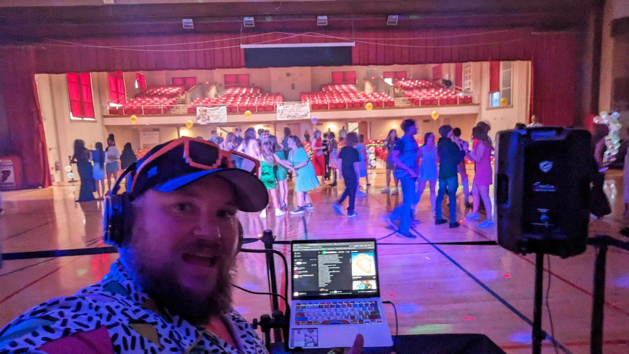 “Students dancing under colorful lights at a middle school dance hosted by DJ Jazzy Josh.”