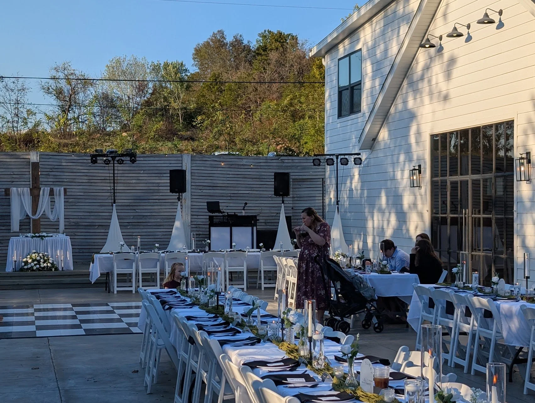 Outdoor wedding dinner setup with white linens and DJ booth ready for the evening.