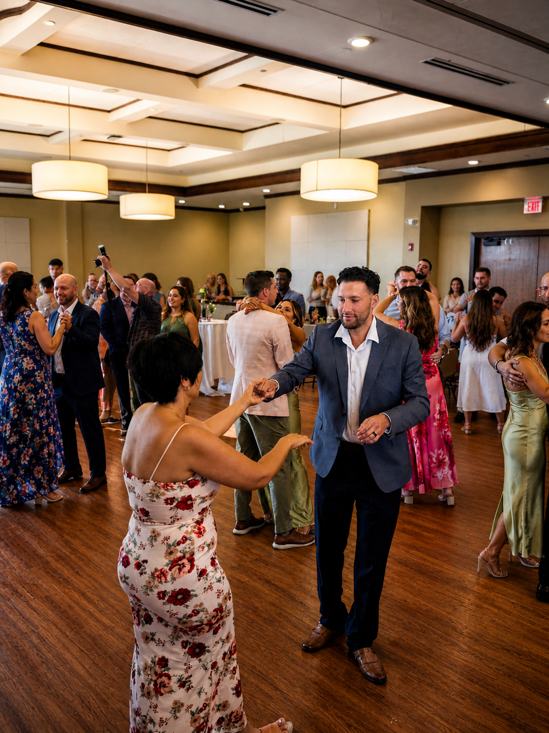 Wedding guests dancing during a lively reception with professional DJ entertainment, elegant ballroom lighting, and packed dance floor energy