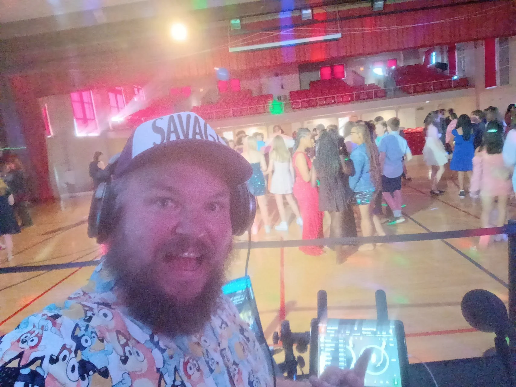 “DJ Jazzy Josh hosting a school dance with students dancing under neon lights.”